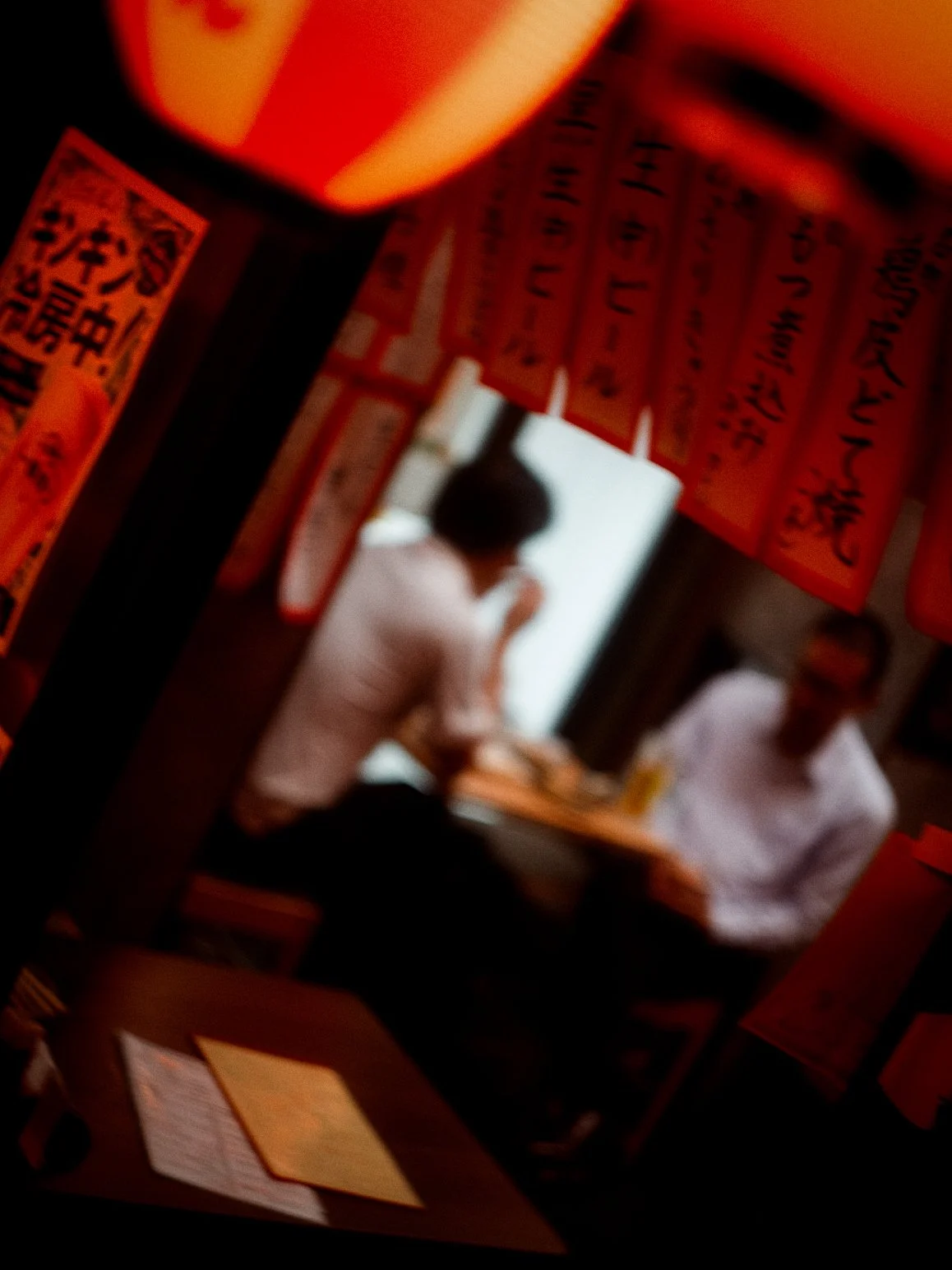 People sitting at a table inside a restaurant with red lanterns and Asian-style decorations.