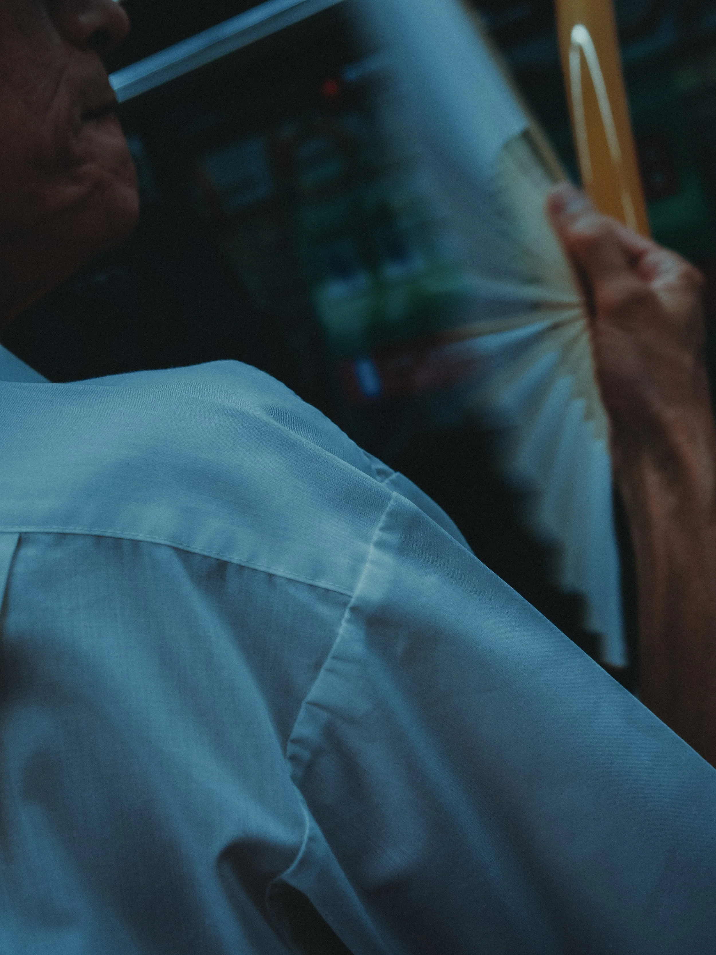 Close-up of a Japanese businessman strying to cool himself on a train using a Japanese hand held fan, a Sensu