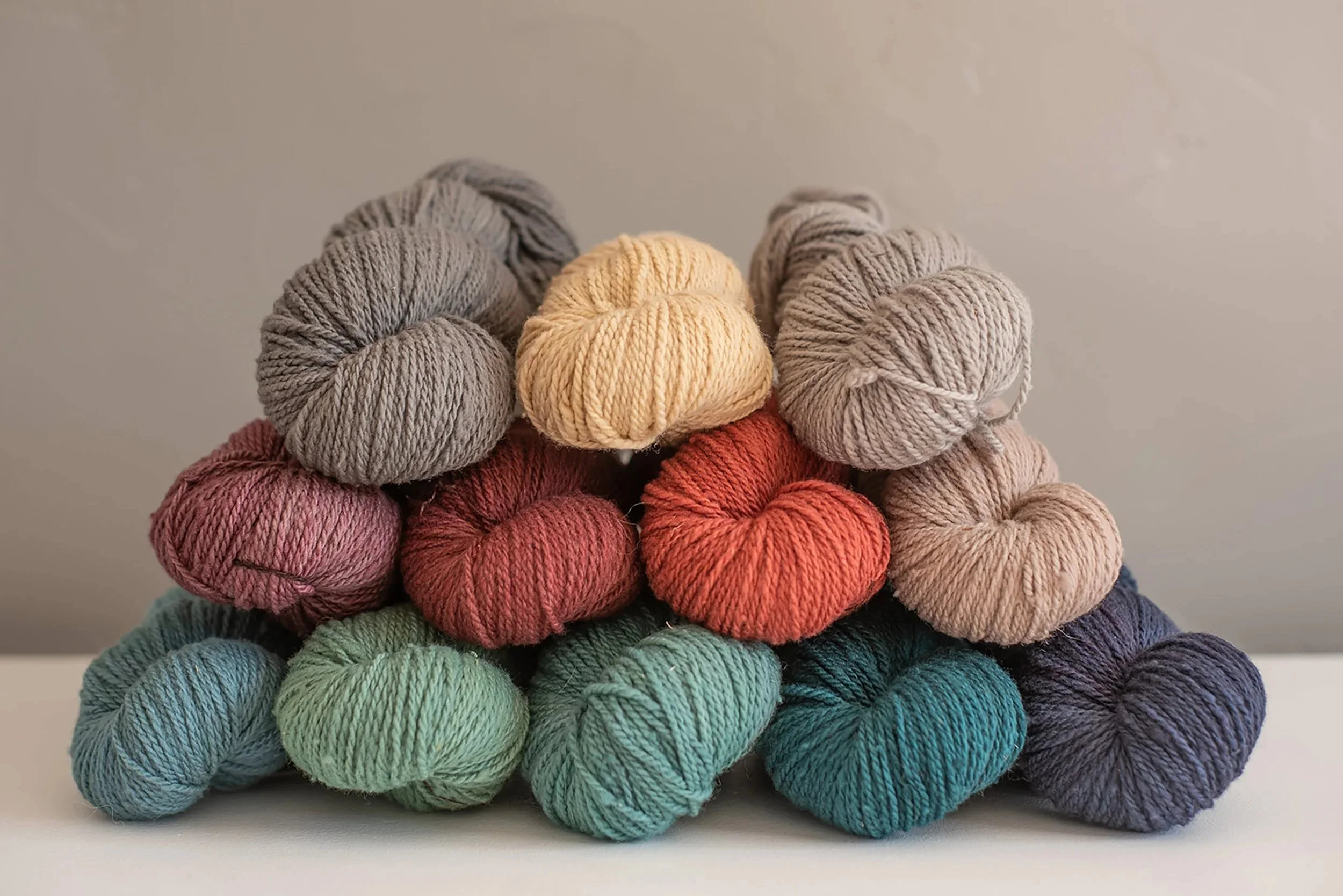 Stacked skeins of wool yarn in muted earth tone colors