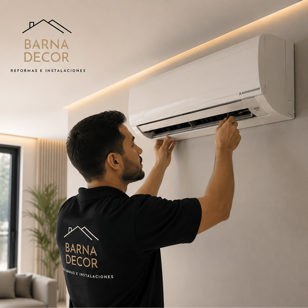 Un hombre instala o repara una unidad de aire acondicionado en la pared de una casa moderna. Lleva una camisa negra con el logotipo de "Barna Decor"