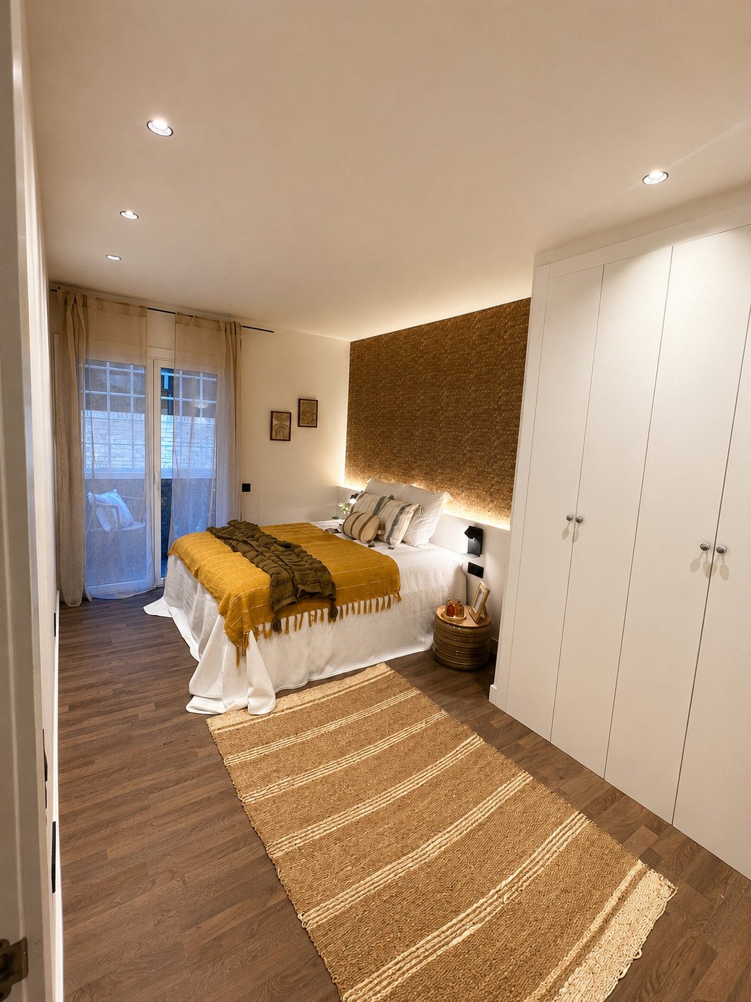 Dormitorio reformado con iluminación integrada, carpintería a medida y acabados contemporáneos realizados por Reformas Barna Decor.