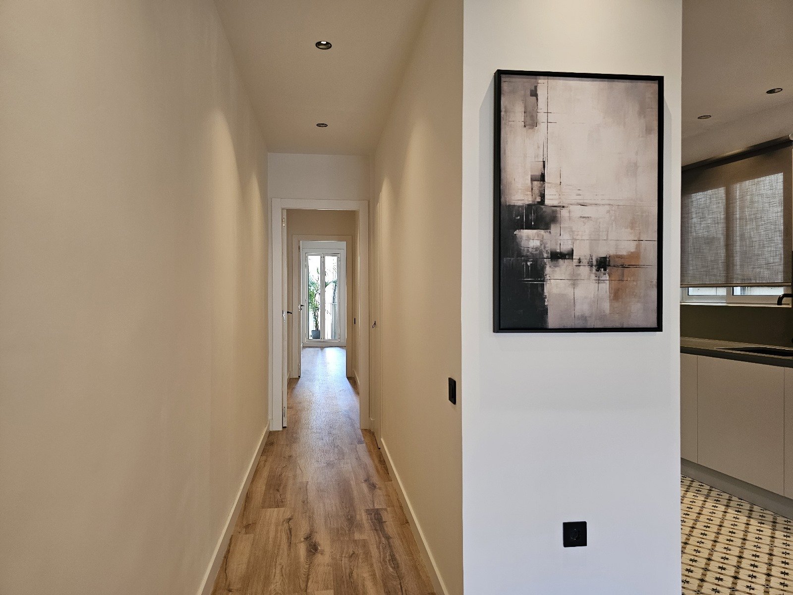 Reforma integral de pasillo con nuevos suelos, pintura, iluminación y acabados modernos dentro de una vivienda en Barcelona.