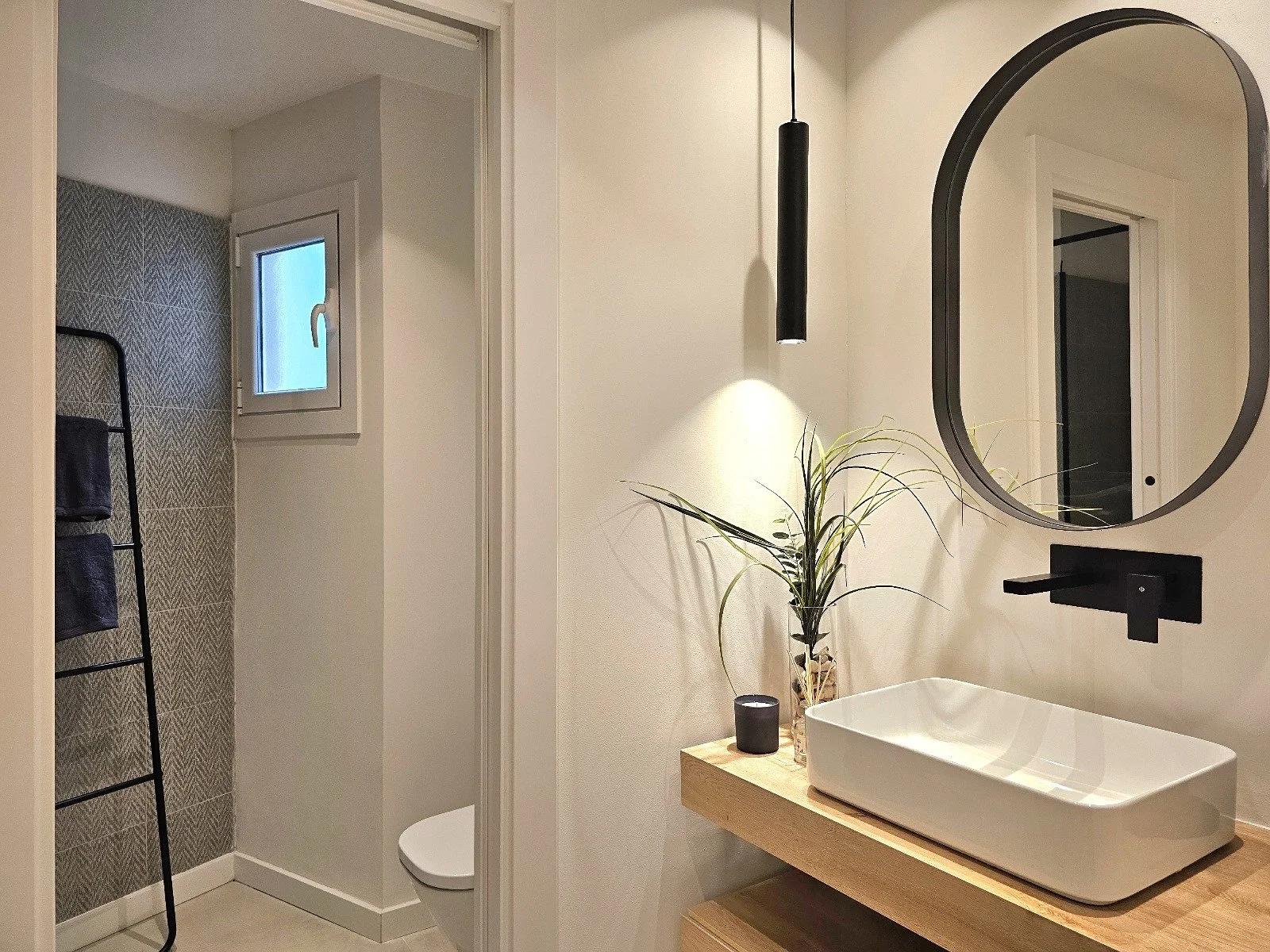Reforma de baño moderno con mobiliario suspendido, lavabo sobre encimera, espejo de diseño e iluminación integrada realizada por Reformas Barna Decor.