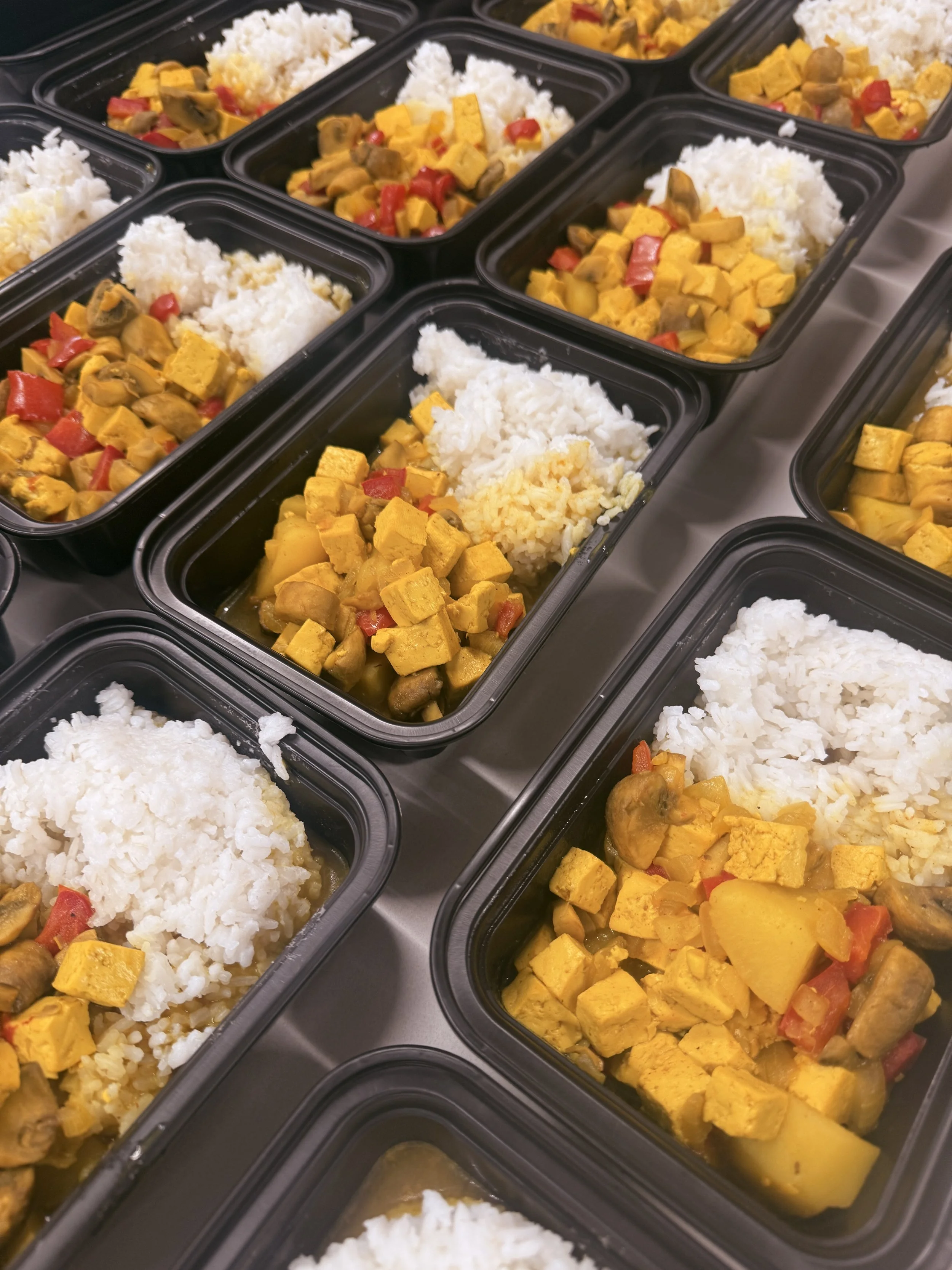 Prepared meals stacked next to each other. The food inside is rice and chicken with peppers in it.