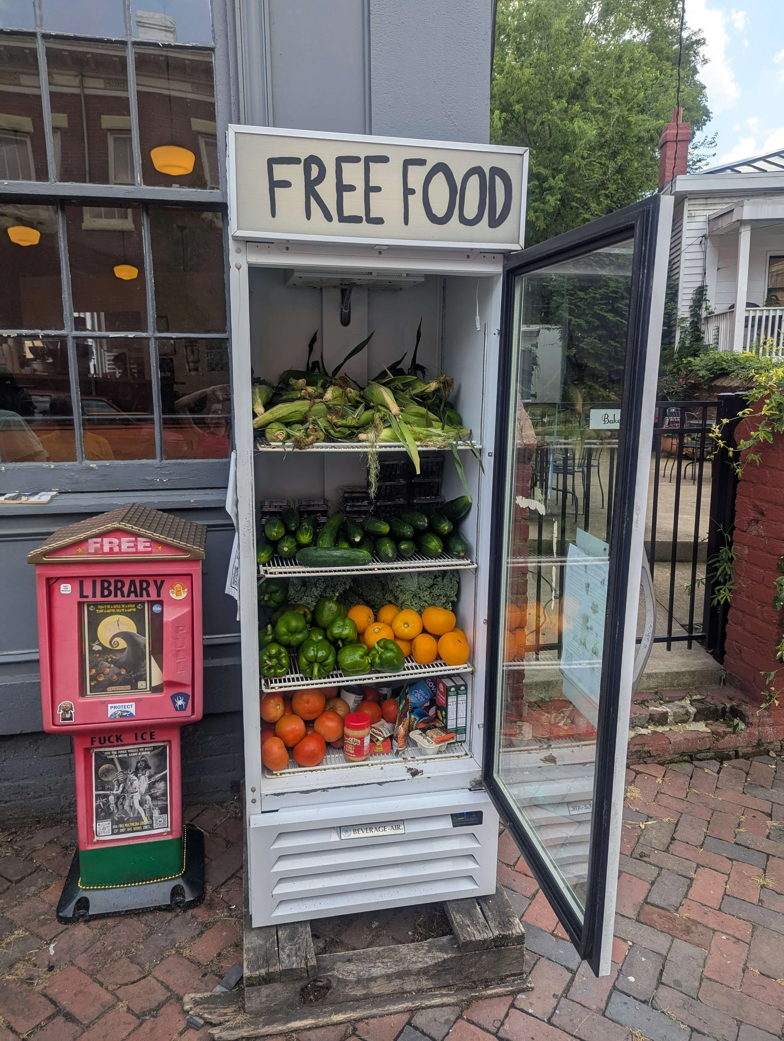 A fridge filled with vegetables with a small pantry willed with dry goods next to it