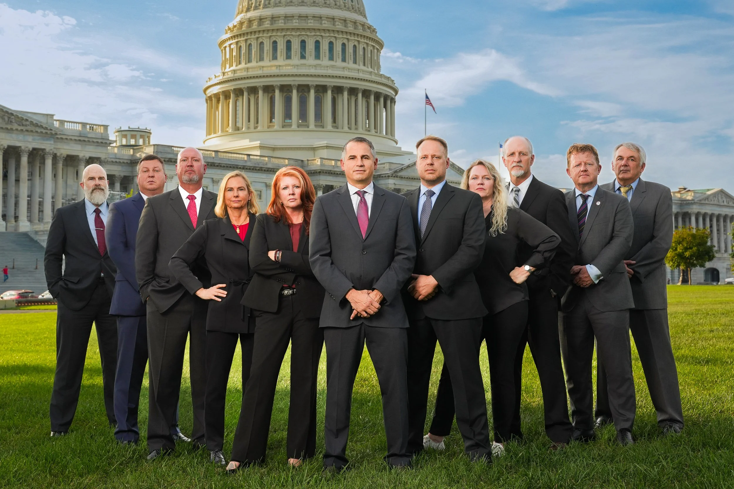 A group of eleven people in business attire standing outside the U.S. Capitol building in Washington D.C. during daytime.