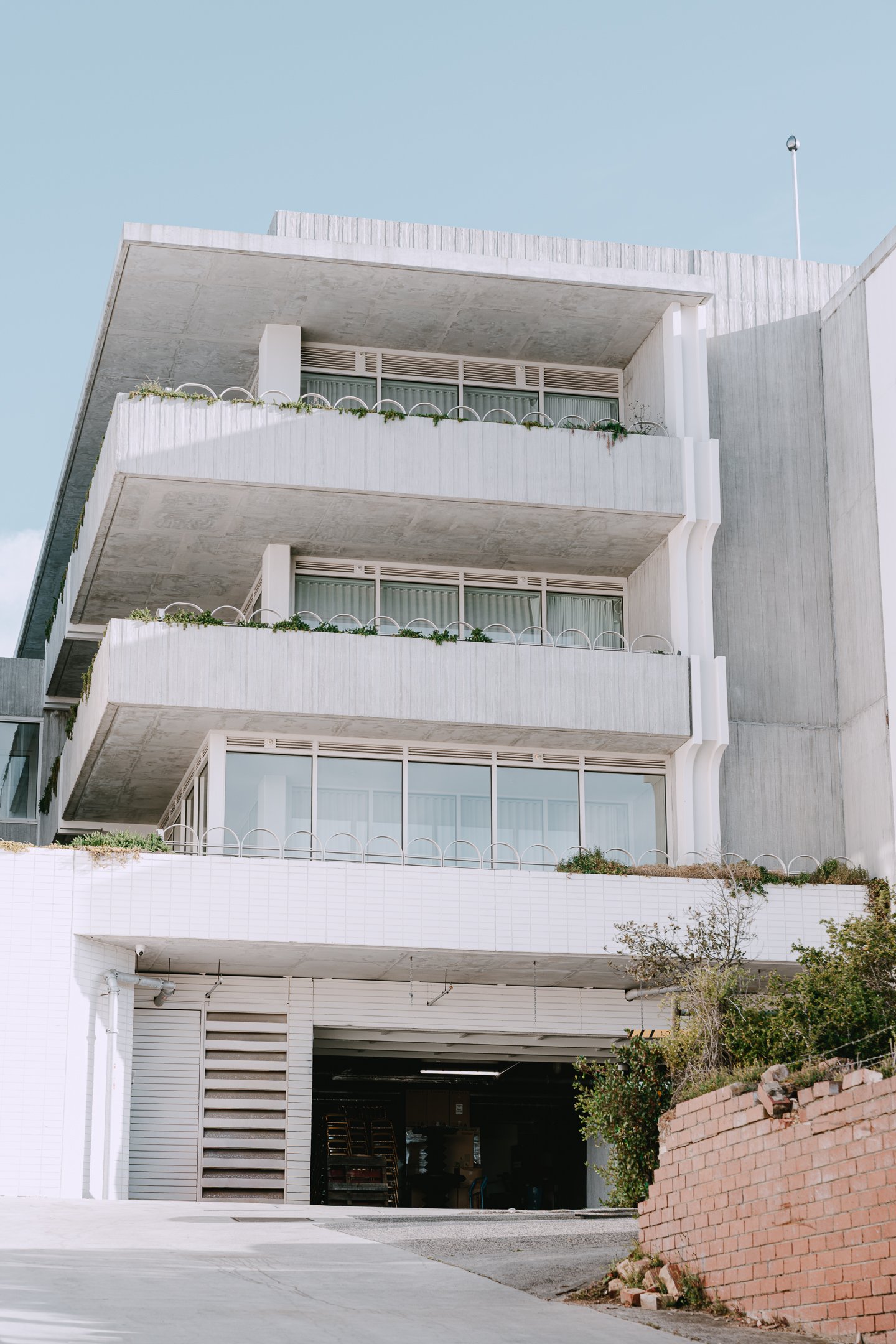 Multi-story modern building with white concrete balconies and large glass windows, for Intercontinental Sorrento, set against a clear blue sky.