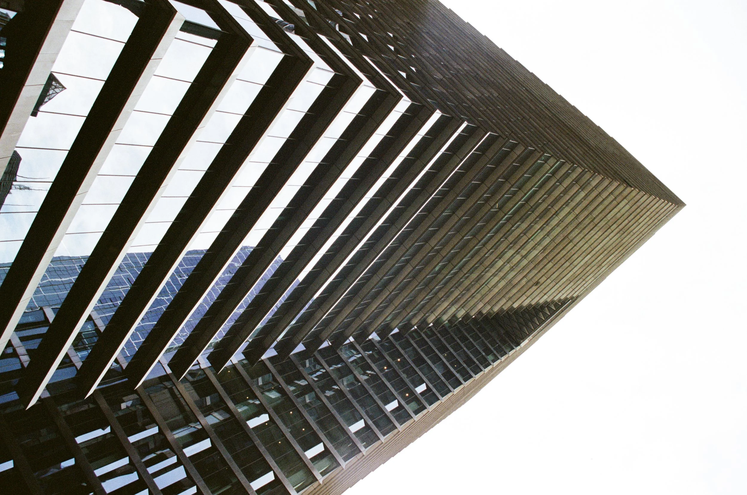 W Melbourne building 408 Flinders Ln, Melbourne. Close-up view of a modern high-rise building with a unique grid-like facade, featuring glass windows and metal framework, taken from a low angle against the sky.