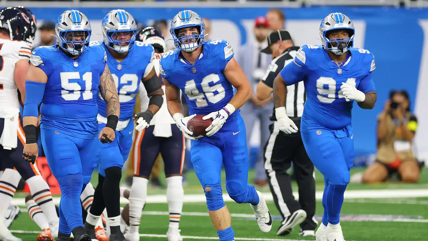 Detroit Lions football players celebrating on the field after a game, wearing blue jerseys and helmets.
