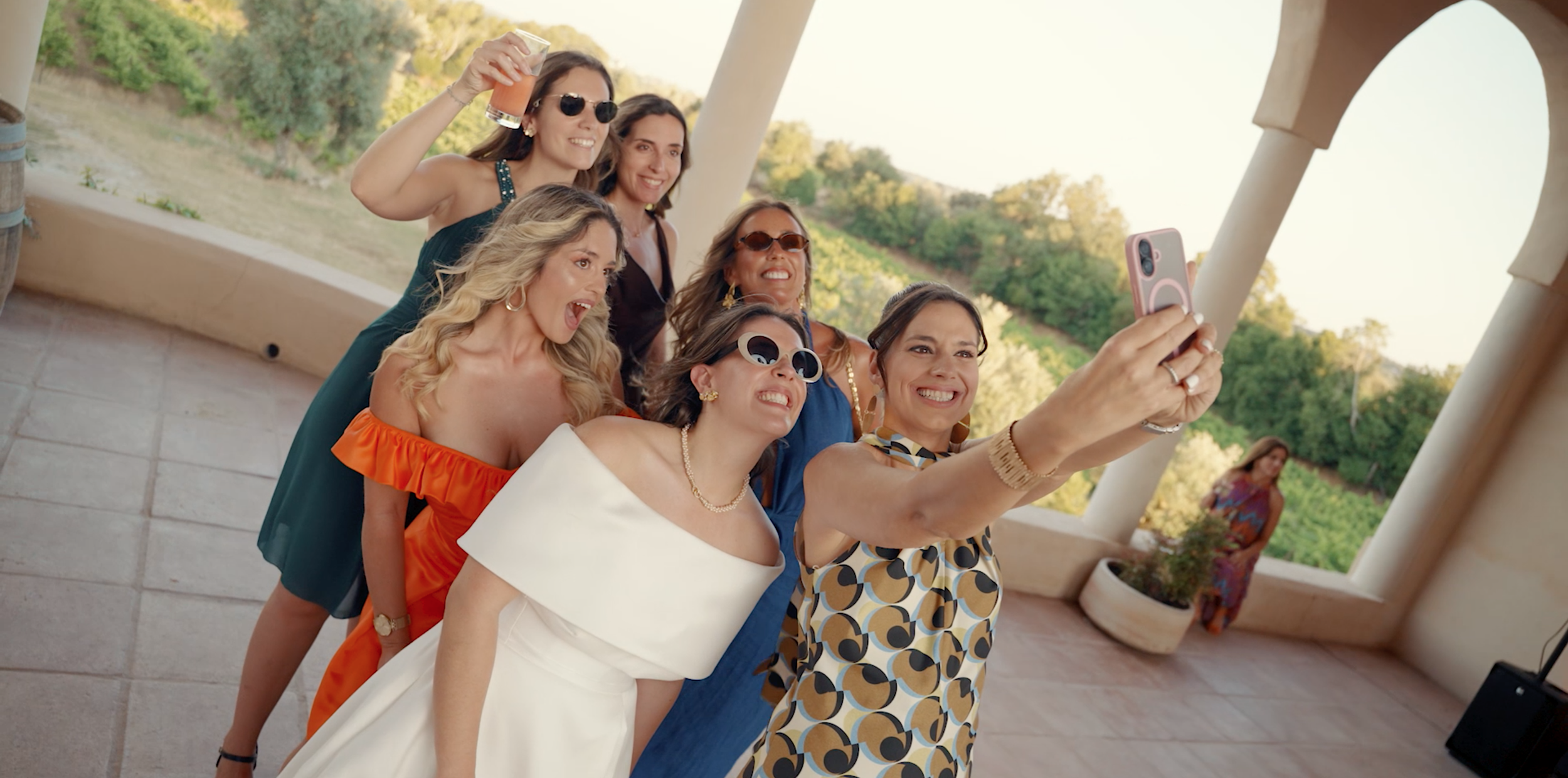A group of women taking a selfie outdoors on a sunny day, smiling and posing together.