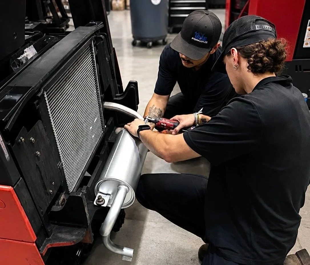 Certified Pinnacle MHS forklift technicians working on muffler replacement in Hyster forklift.