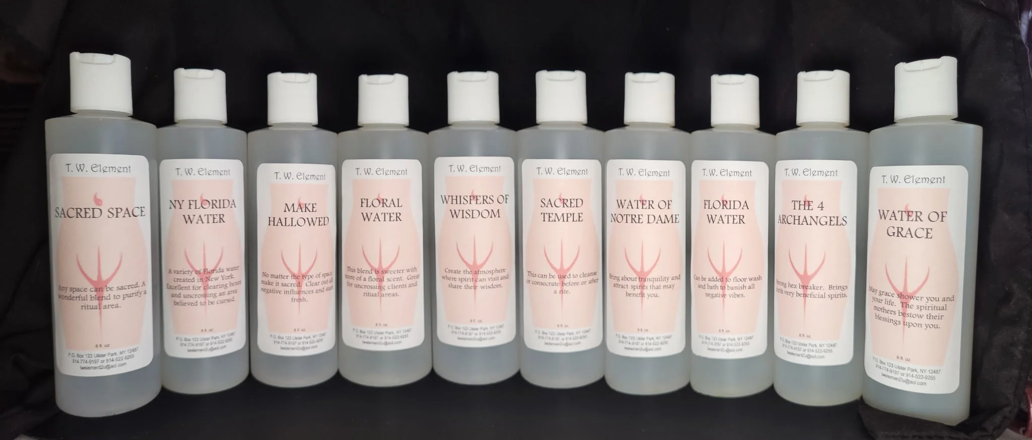 Nine bottles of ritual or spiritual water labeled with various names such as 'Sacred Space,' 'NY Florida Water,' 'Make Hallowed,' 'Floral Water,' 'Whispers of Wisdom,' 'Sacred Temple,' 'Water of Notre Dame,' 'Florida Water,' and 'Water of Grace.' Each bottle has a pink symbol resembling a three-pronged trident or pitchfork.