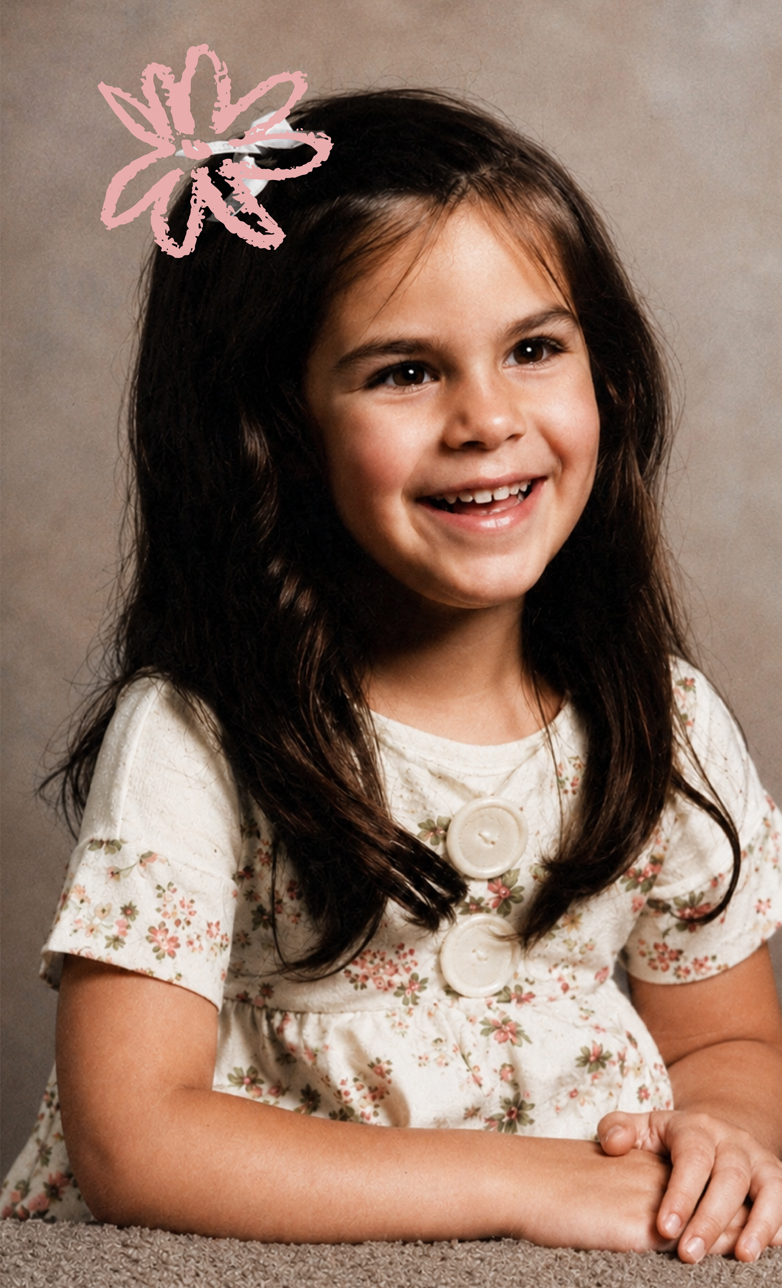 Jeune fille souriante aux cheveux bruns longs, portant une robe à fleurs avec de gros boutons, assise avec ses bras croisés sur une surface en tapis.