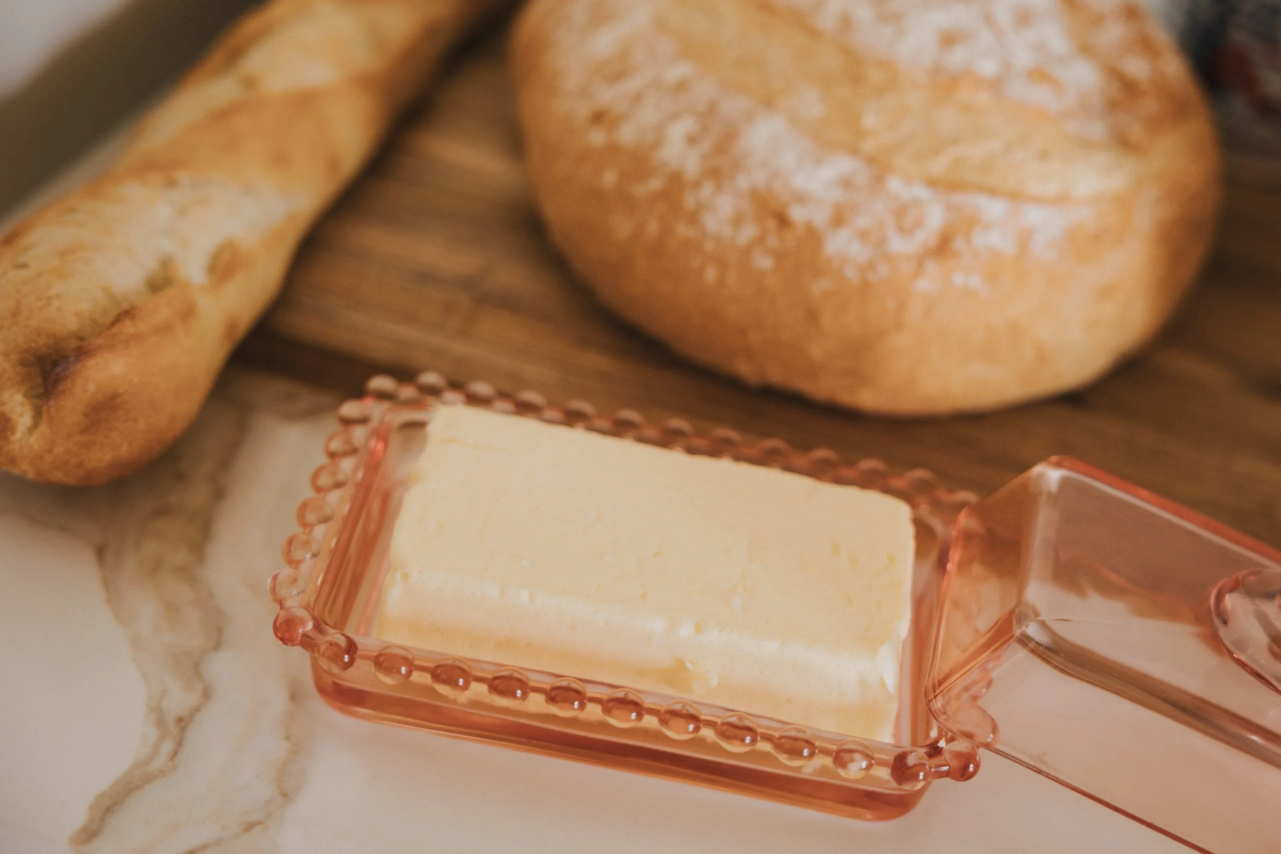 Fromage blanc dans un plat en verre rose, à côté de pains et d'une sauce.