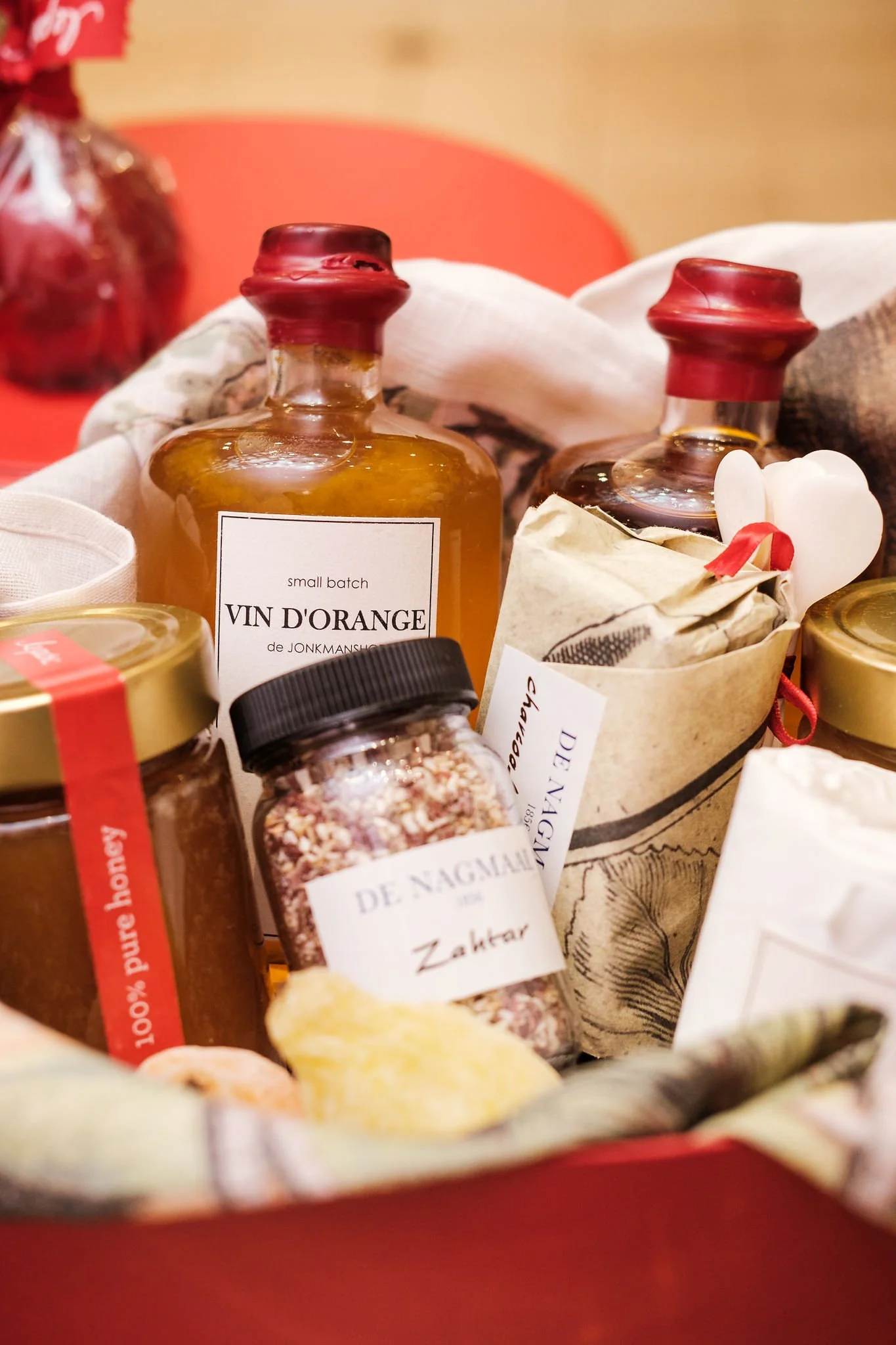 Close-up of small glass bottles with red wax seals, containing various spices and ingredients, wrapped in decorative paper and arranged in a bowl.