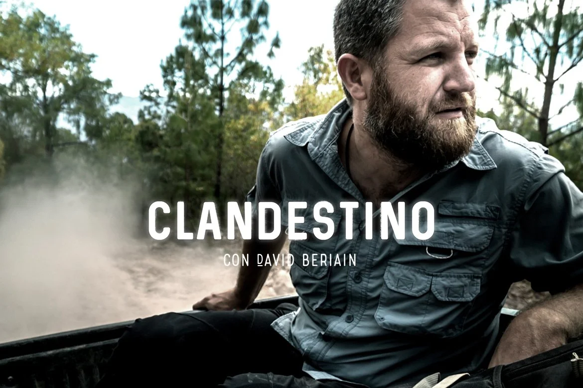 Hombre con barba y camisa en un bosque, en movimiento en un vehículo off-road durante el día.