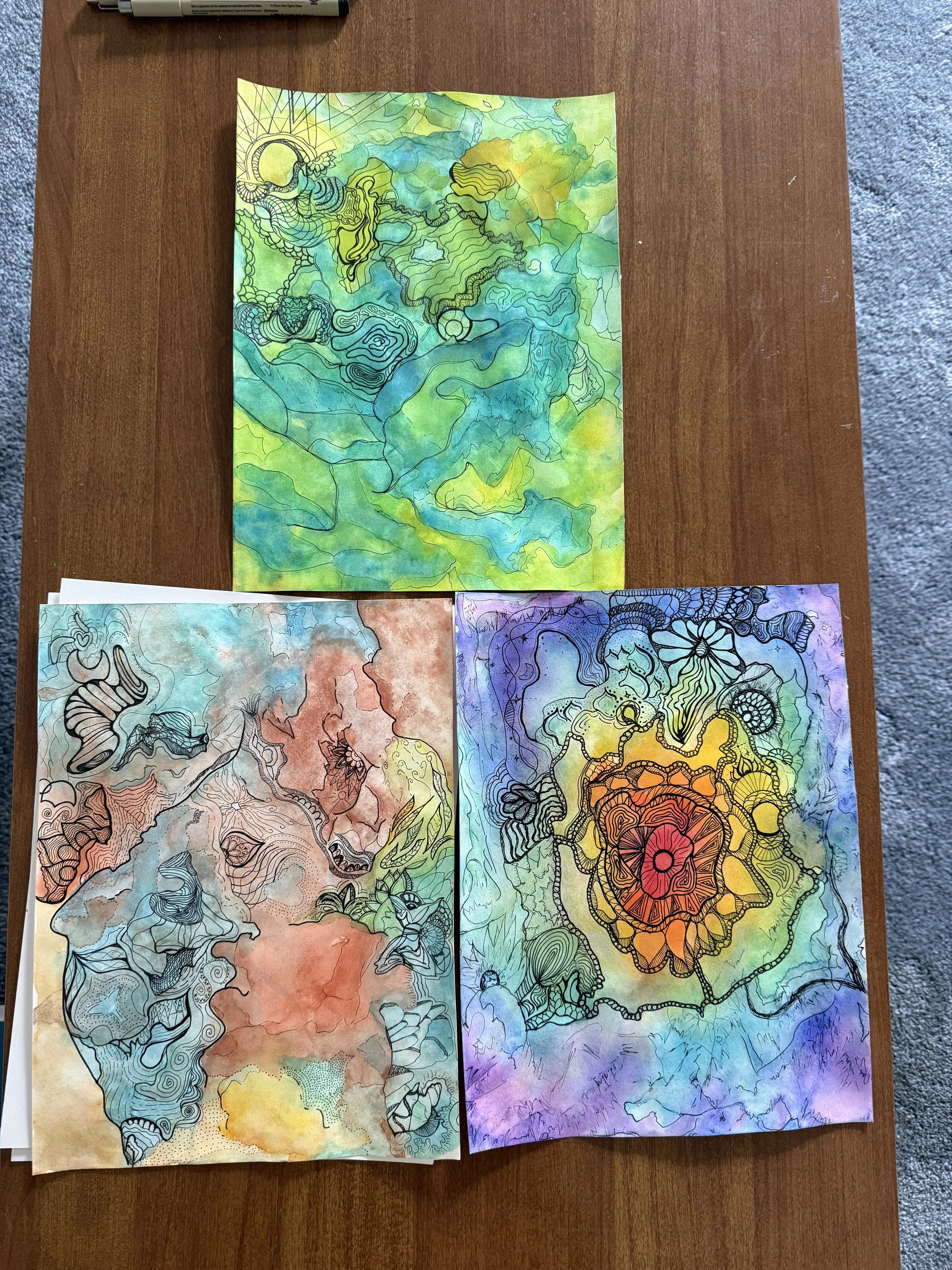 Three colorful watercolor and ink artworks displayed together.