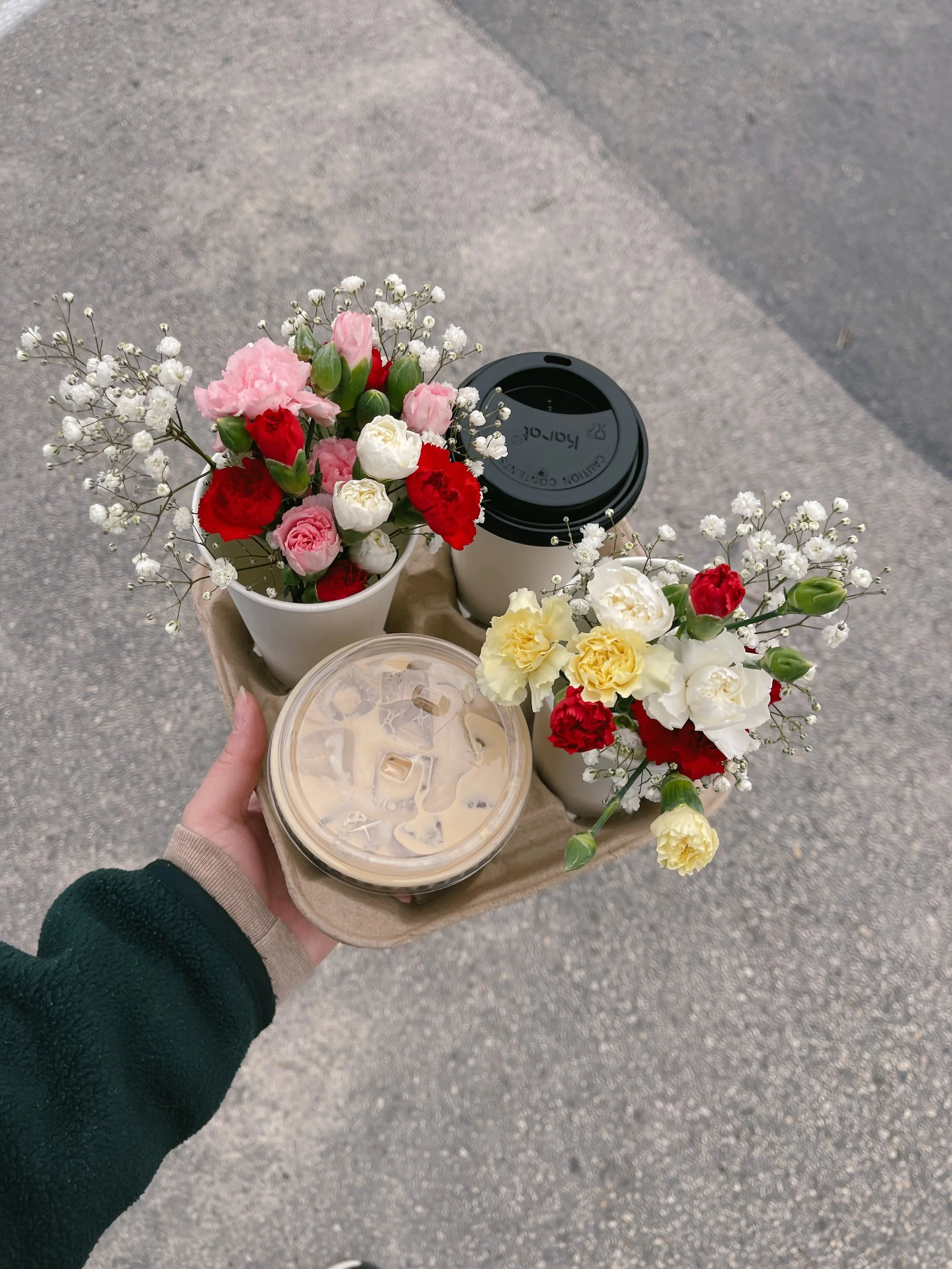 A person holding a tray with two small wildflower bouquets and two iced coffee drinks in Tennessee.