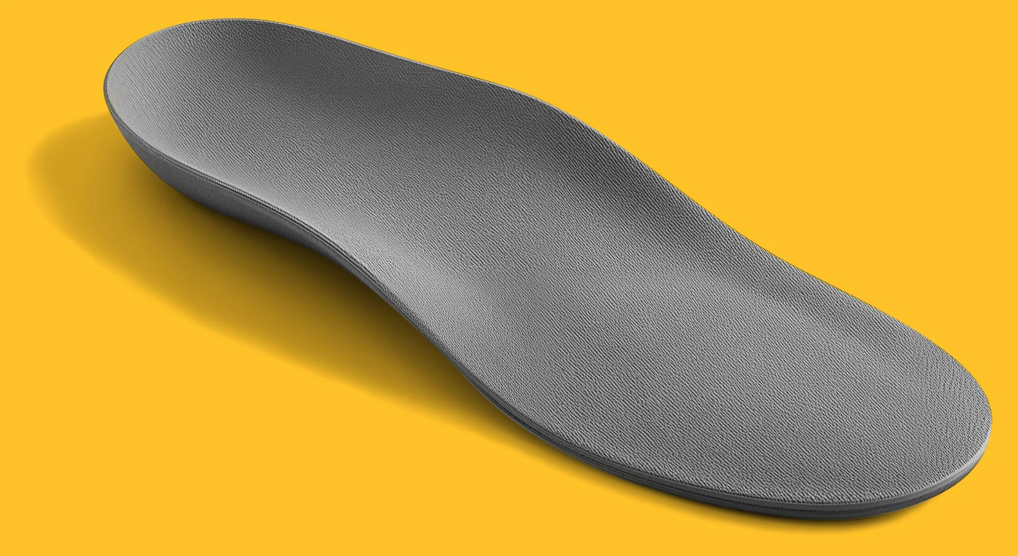 A close-up of a grey textured insole, with a shadow cast on a yellow background.