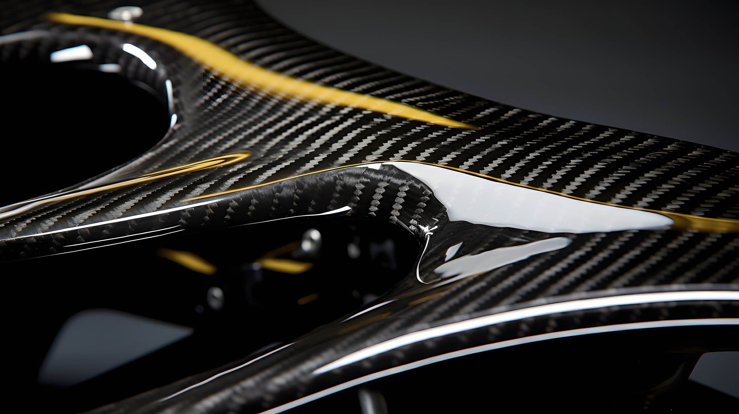 Close-up of a carbon fiber automobile part with yellow accents.
