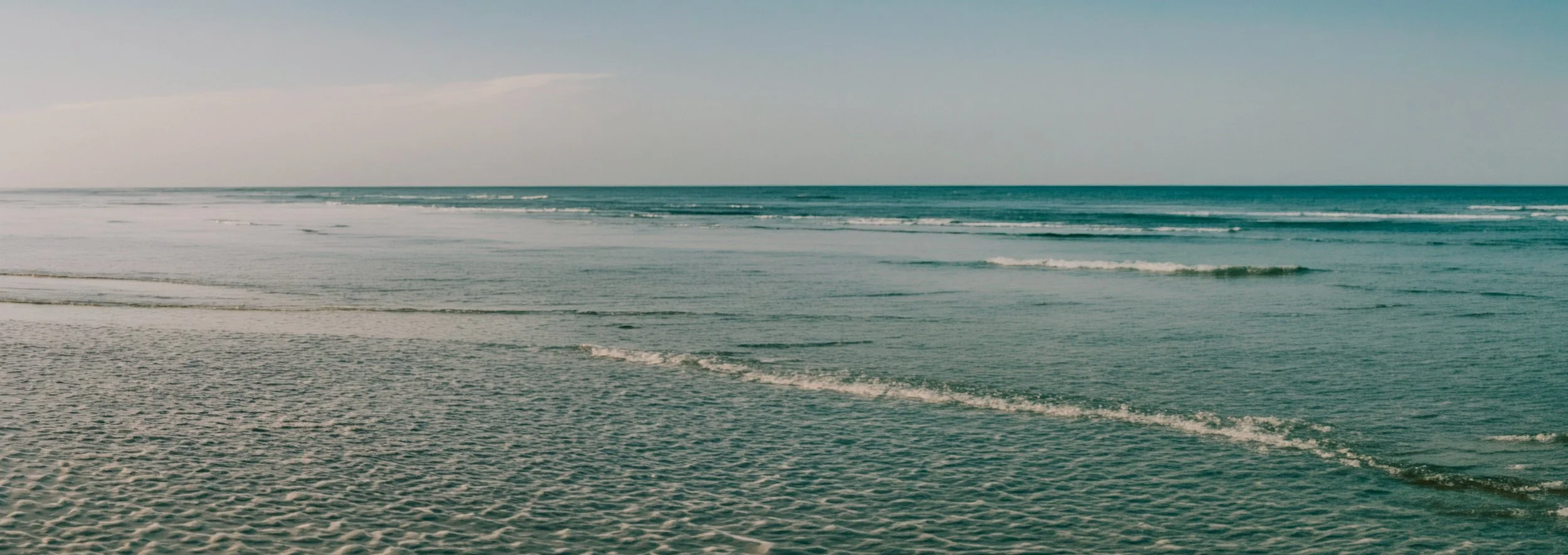 Plage de sable avec des vagues calmes sous un ciel clair