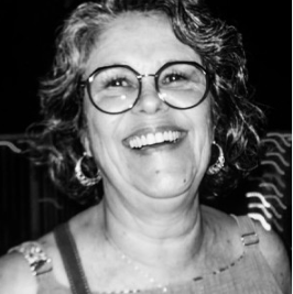 Mulher sorrindo, de cabelo cacheado, usando óculos e brincos, em fotos preto e branco.
