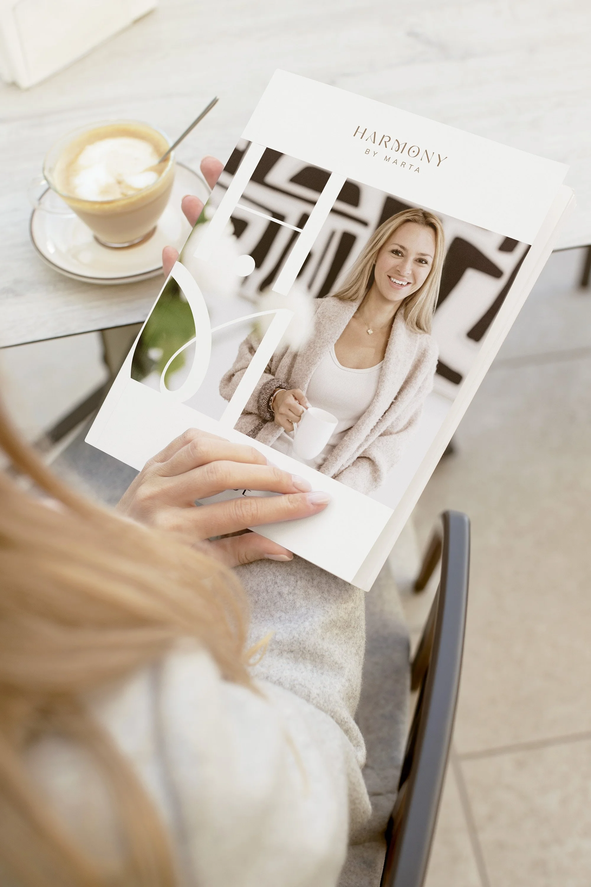 Person holding a magazine featuring a smiling woman holding a coffee cup.