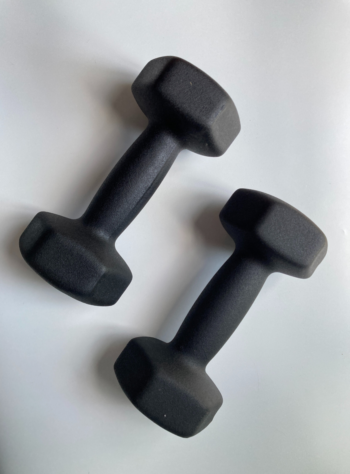 Two black dumbbells placed on a white surface.