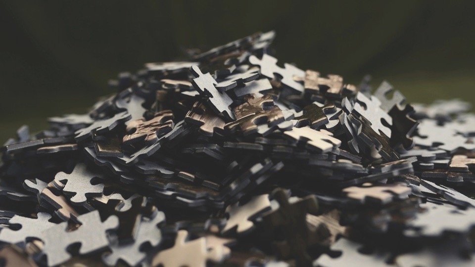 Close-up of a pile of black and beige jigsaw puzzle pieces