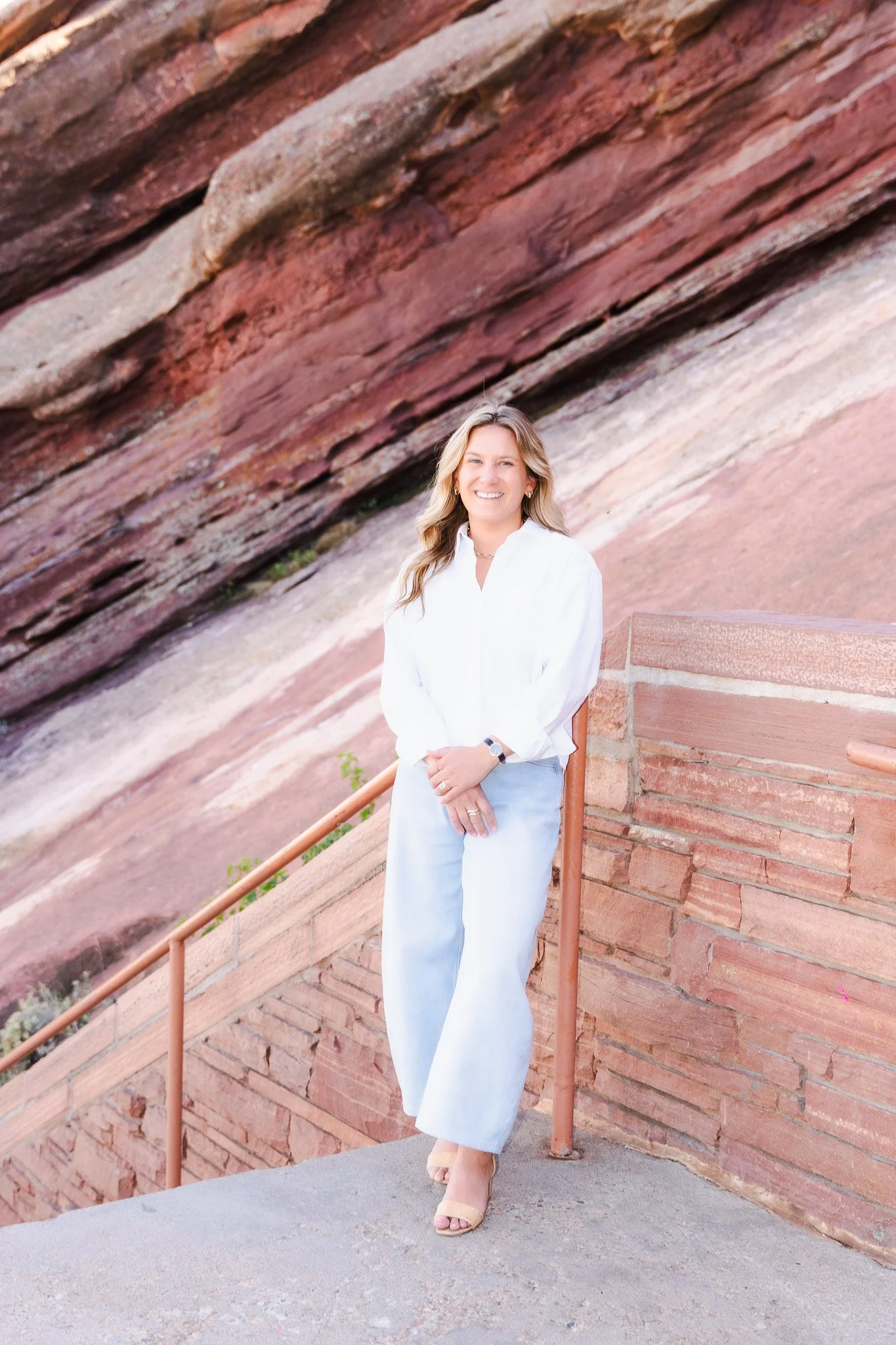 Noelle Juengling in white shirt and jeans standing in front of red rocks