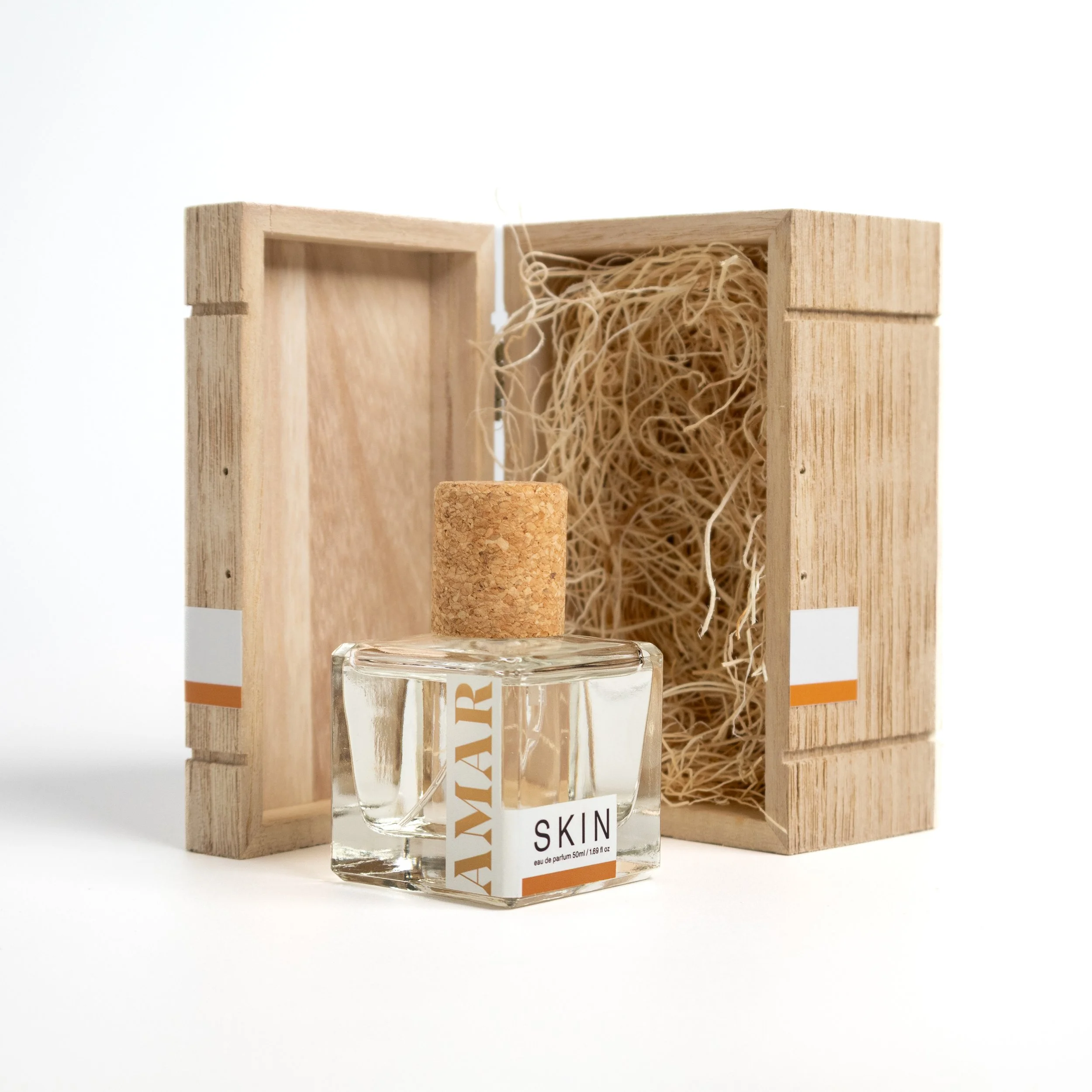 AMAR SKIN Eau de Parfum bottle beside its open wooden packaging box, lined with wood wool