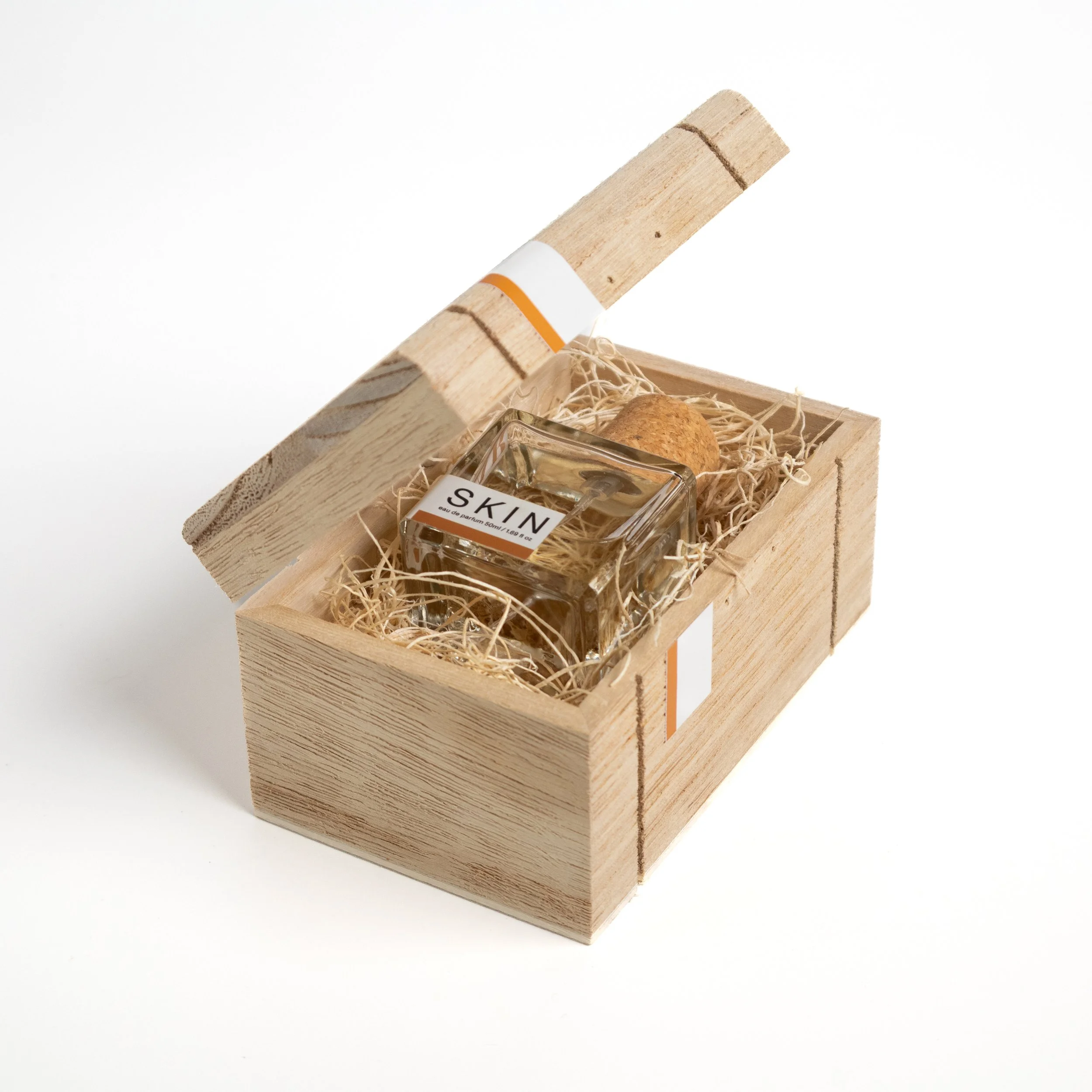 Wooden AMAR box opening to reveal the SKIN Eau de Parfum bottle nestled in wood wool