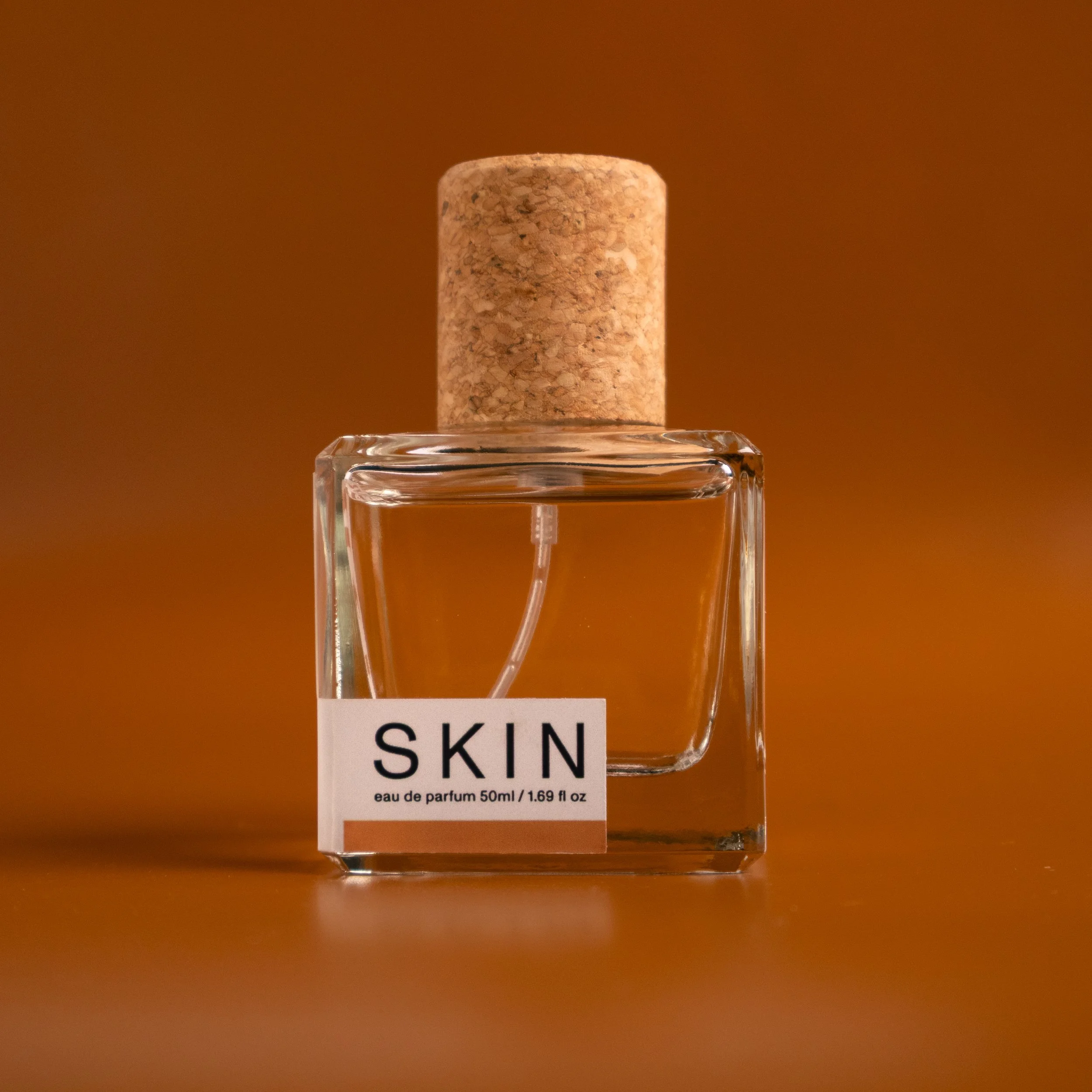 SKIN Eau de Parfum bottle standing against an amber leather background
