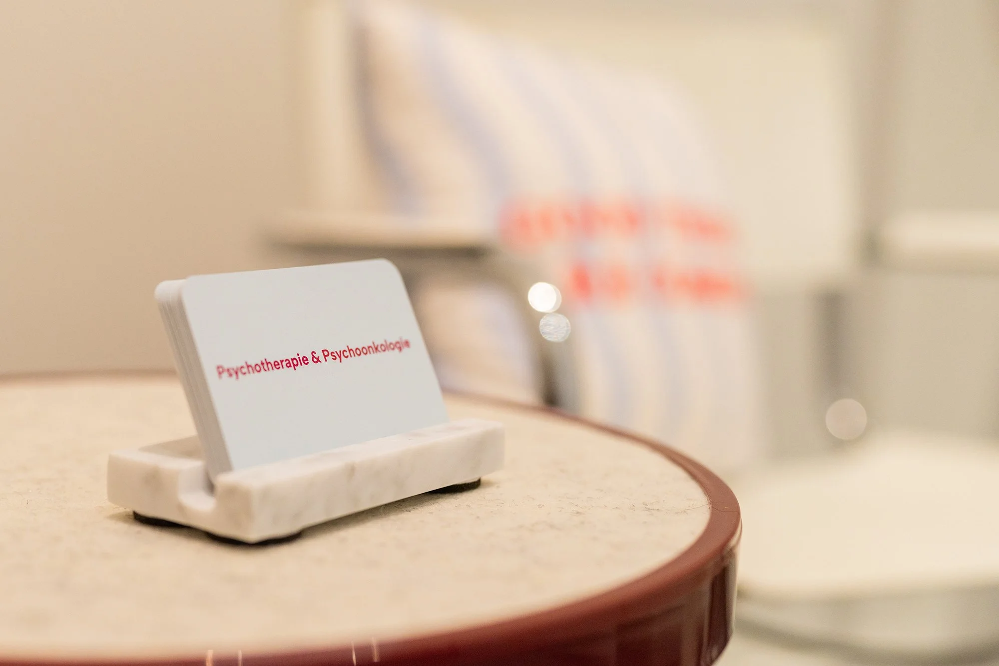 Auf einem Tisch im Wartebereich der Psychotherapiepraxis Sandra Hahn steht ein Visitenkartenhalter. Auschrift: Psychotherapie & Psychoonkologie. (Foto: Tobias Härtel)