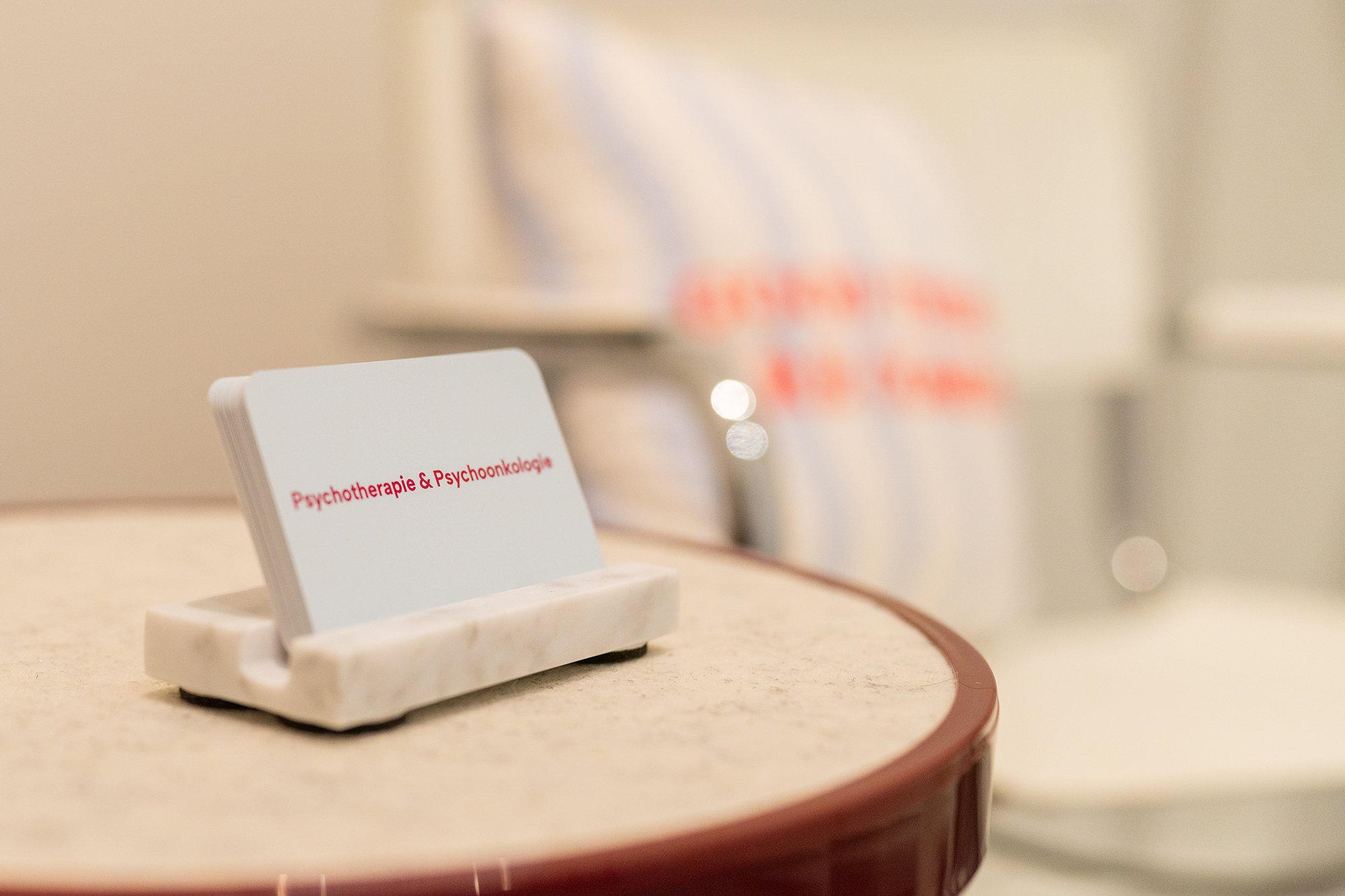 Auf einem Tisch im Wartebereich der Psychotherapiepraxis Sandra Hahn steht ein Visitenkartenhalter. Auschrift: Psychotherapie & Psychoonkologie. (Foto: Tobias Härtel)