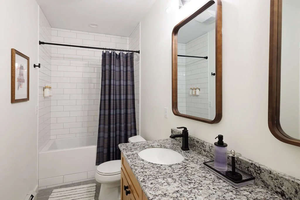 Bathroom with a shower, toilet, granite countertop sink, and two mirrors.