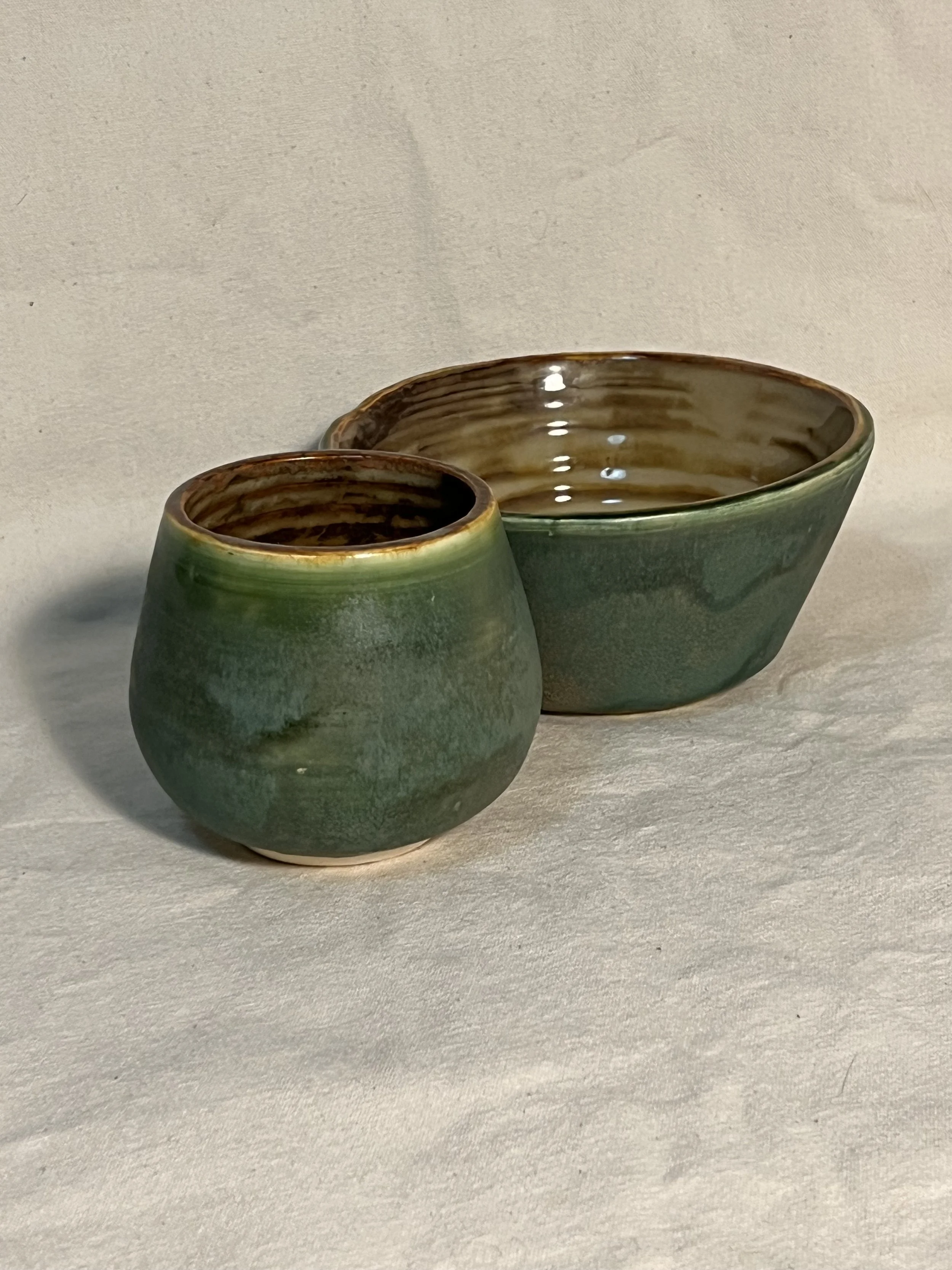 A small cup and bowl set with the same glaze combination of matte teal blue and coffee cream-colored inside