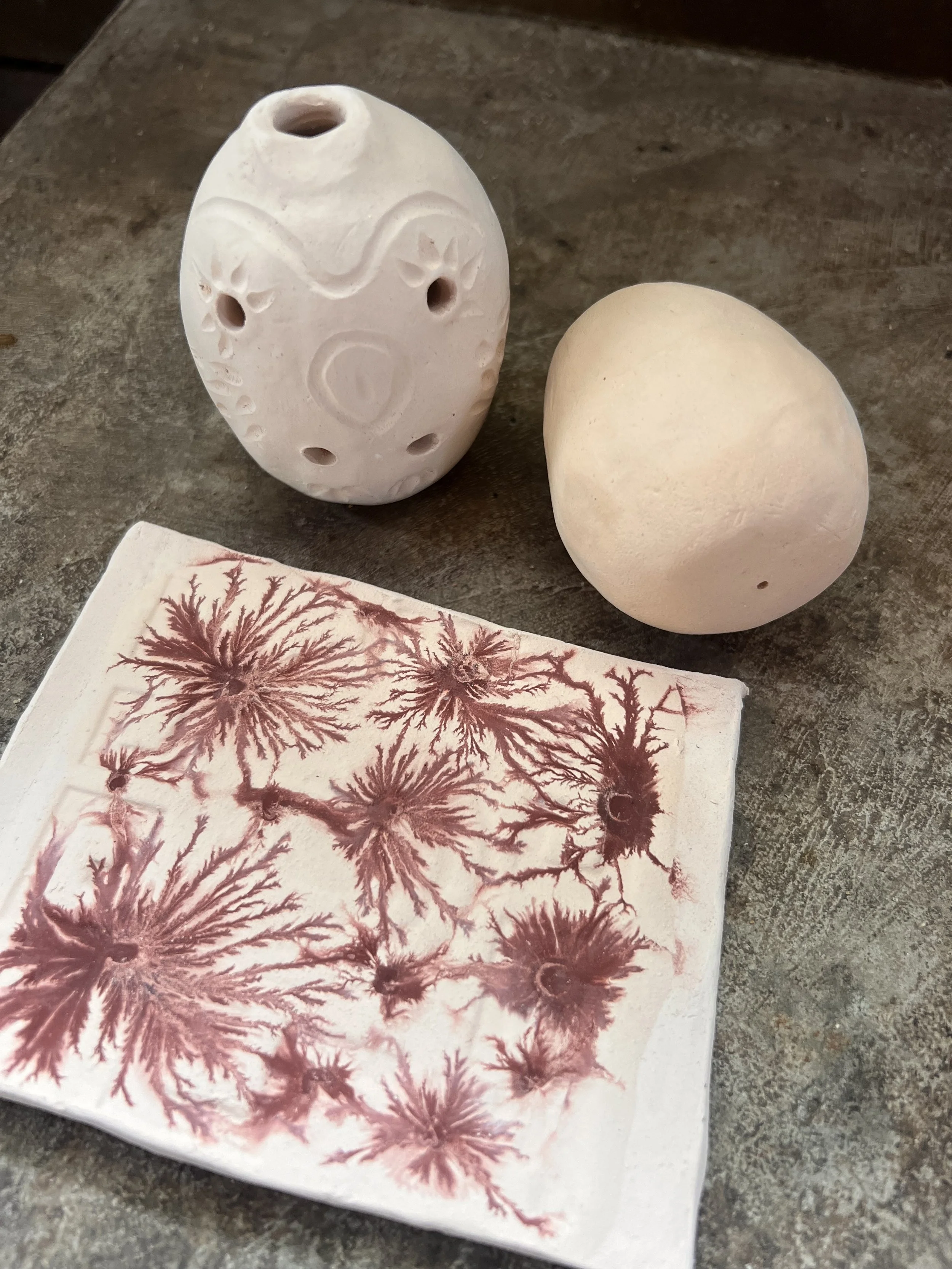 A clay owl whistle, clay shaker instrument, and flat clay piece with tobacco stains