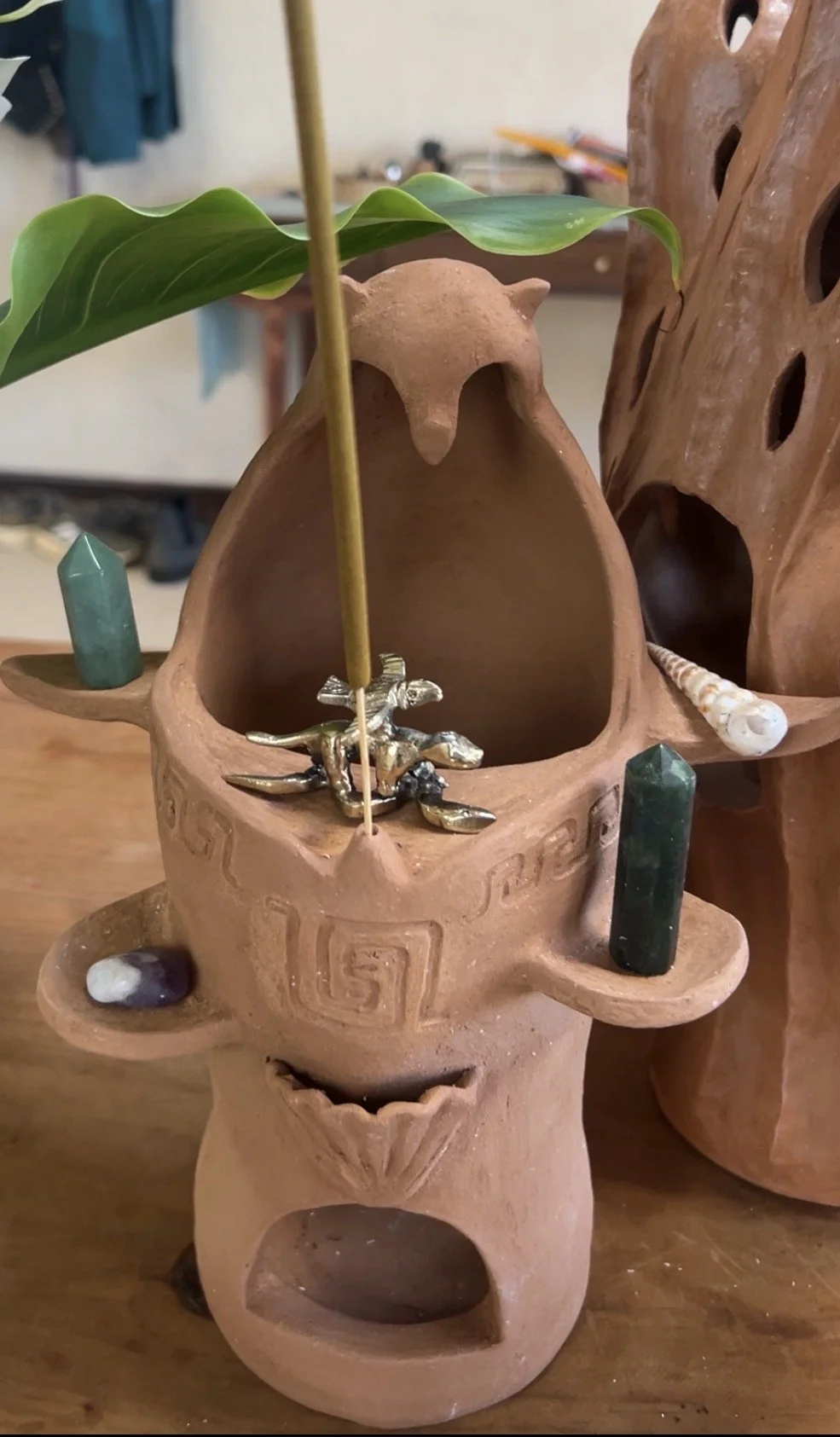 An earthenware sculptural altar with stones, amulets, and incense