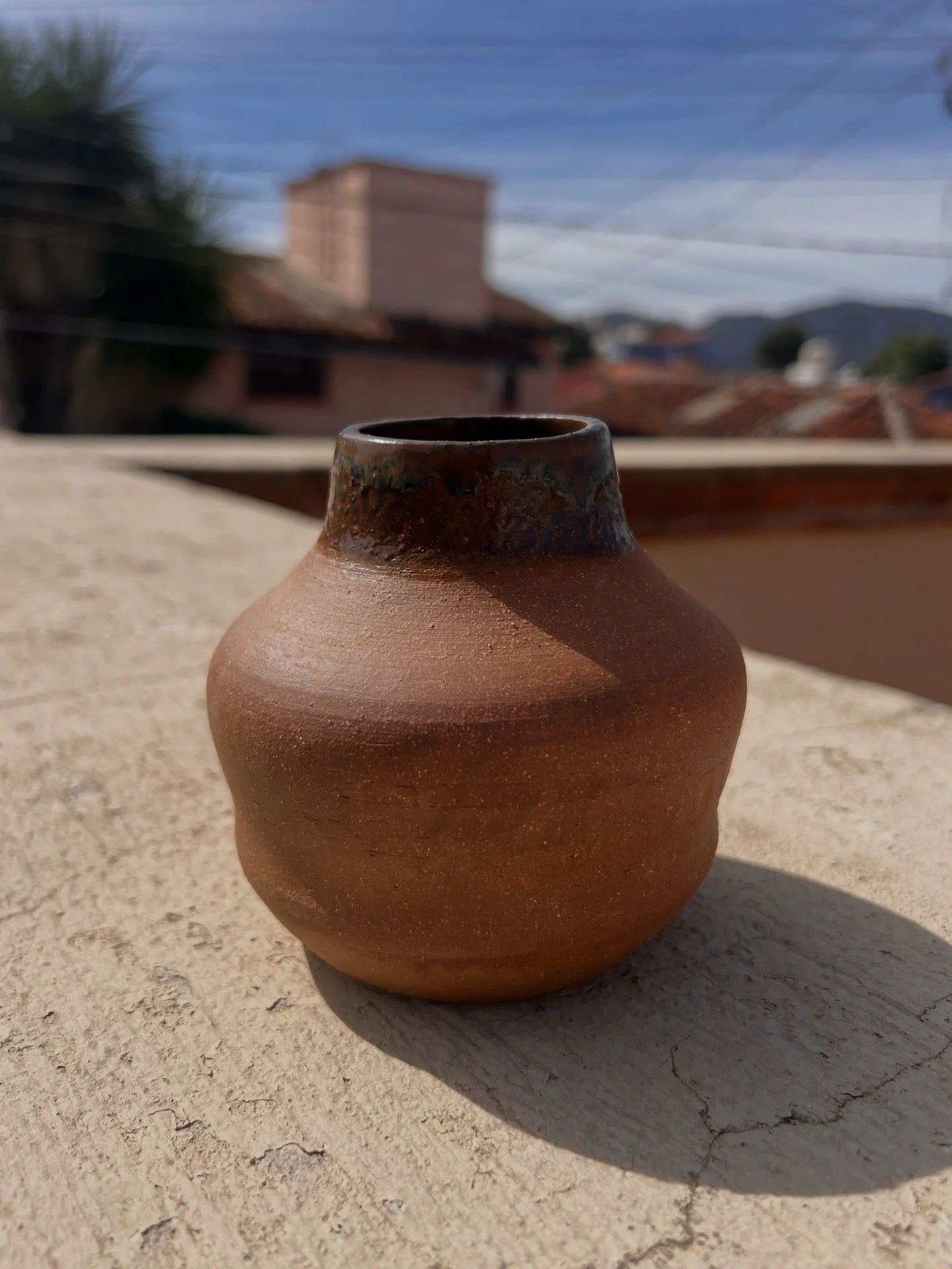 This small bud vase is hand-thrown from red high-fire clay and glazed on the rim.