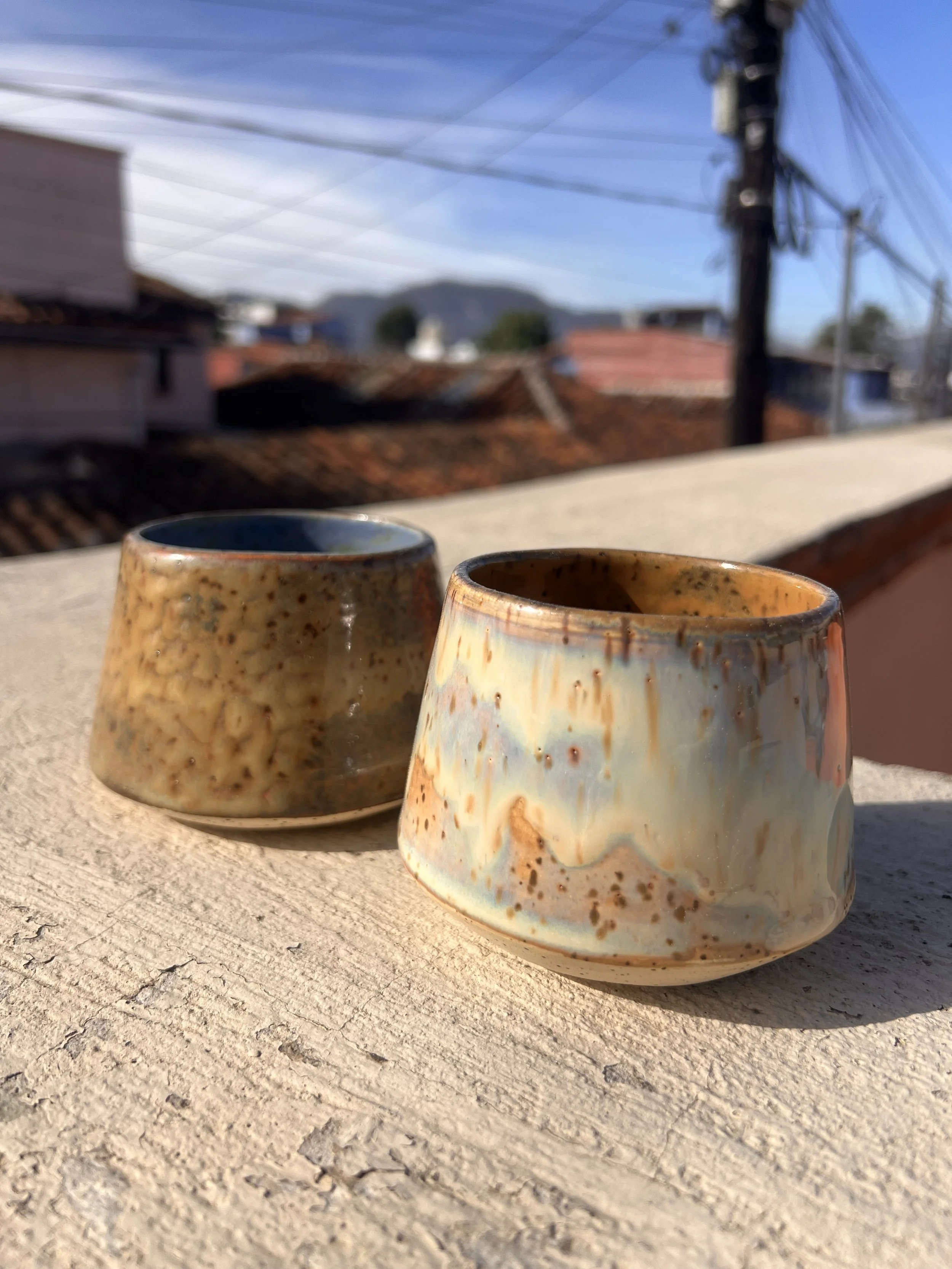 Two medium handle-free mugs show speckle variations in glazes.