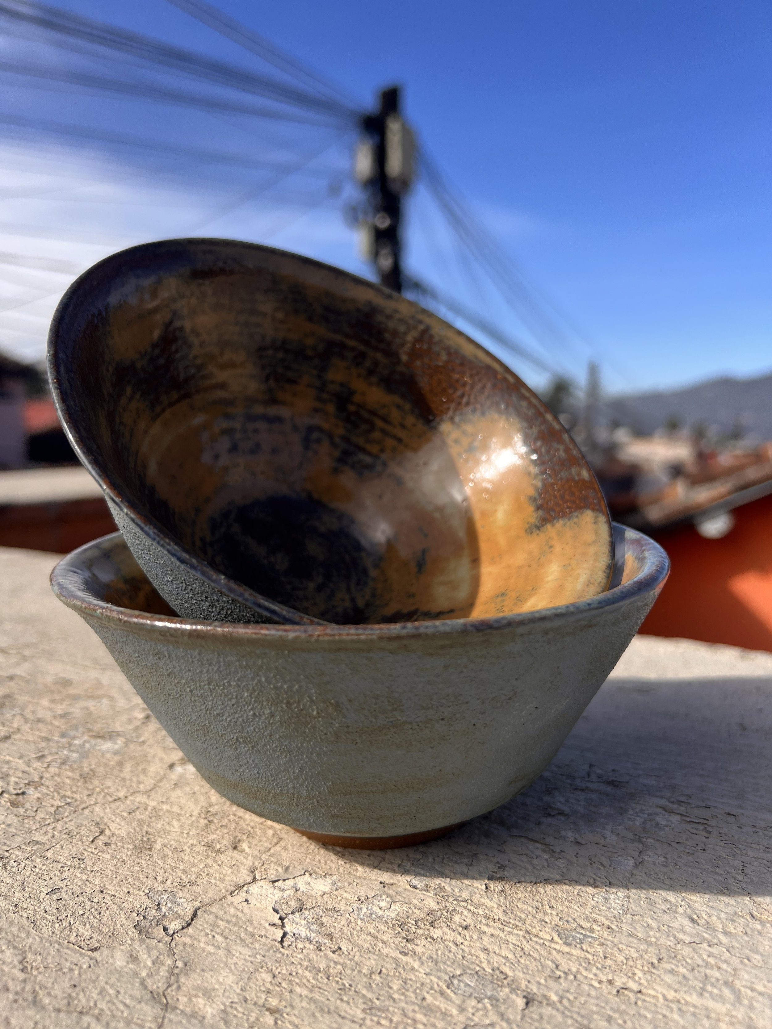 Two high-fired bowls are stacked, showing matte blue and speckled coffee-colored glaze combo.