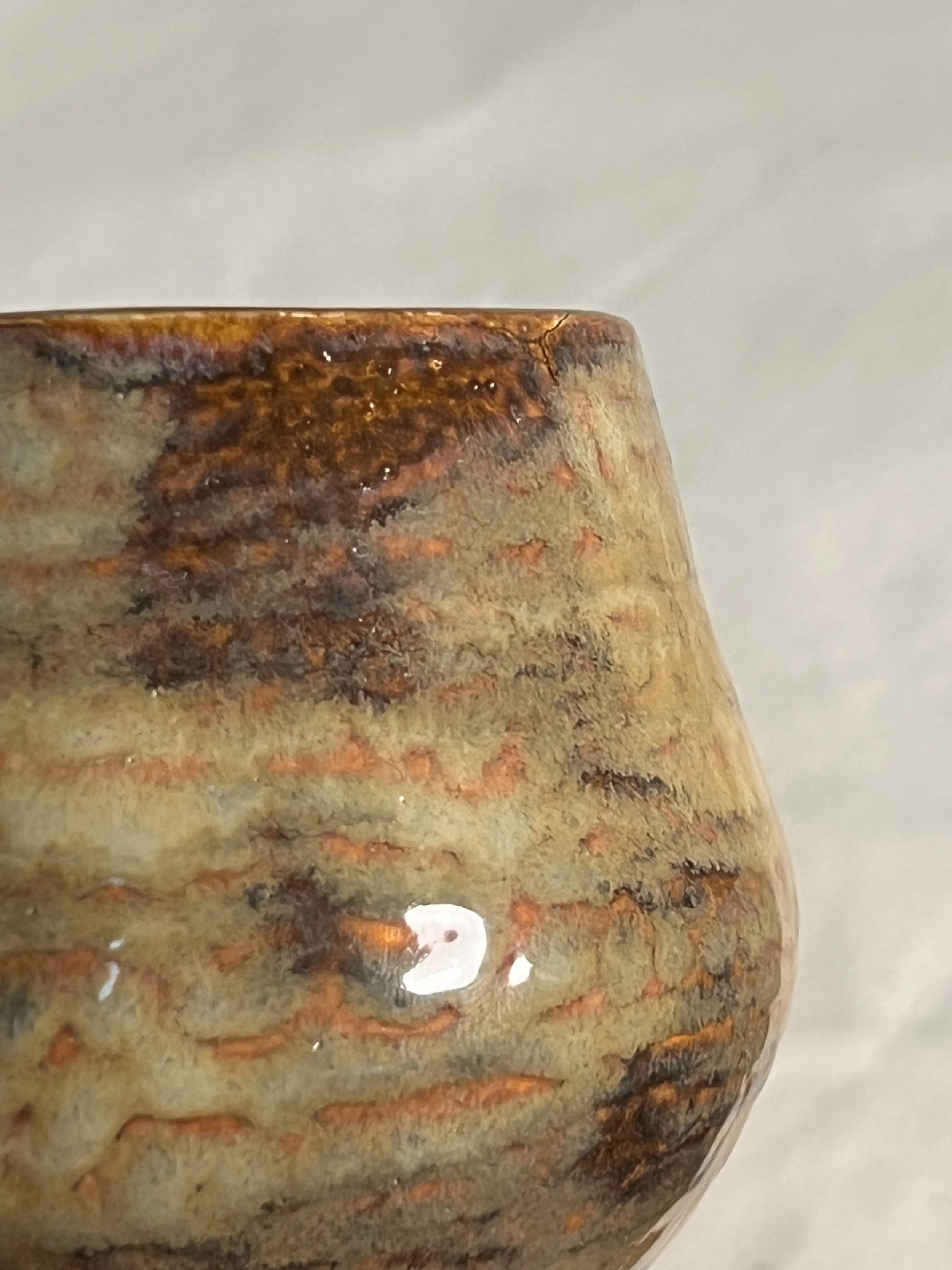 close-up of a small mug with a textured earth-toned glaze