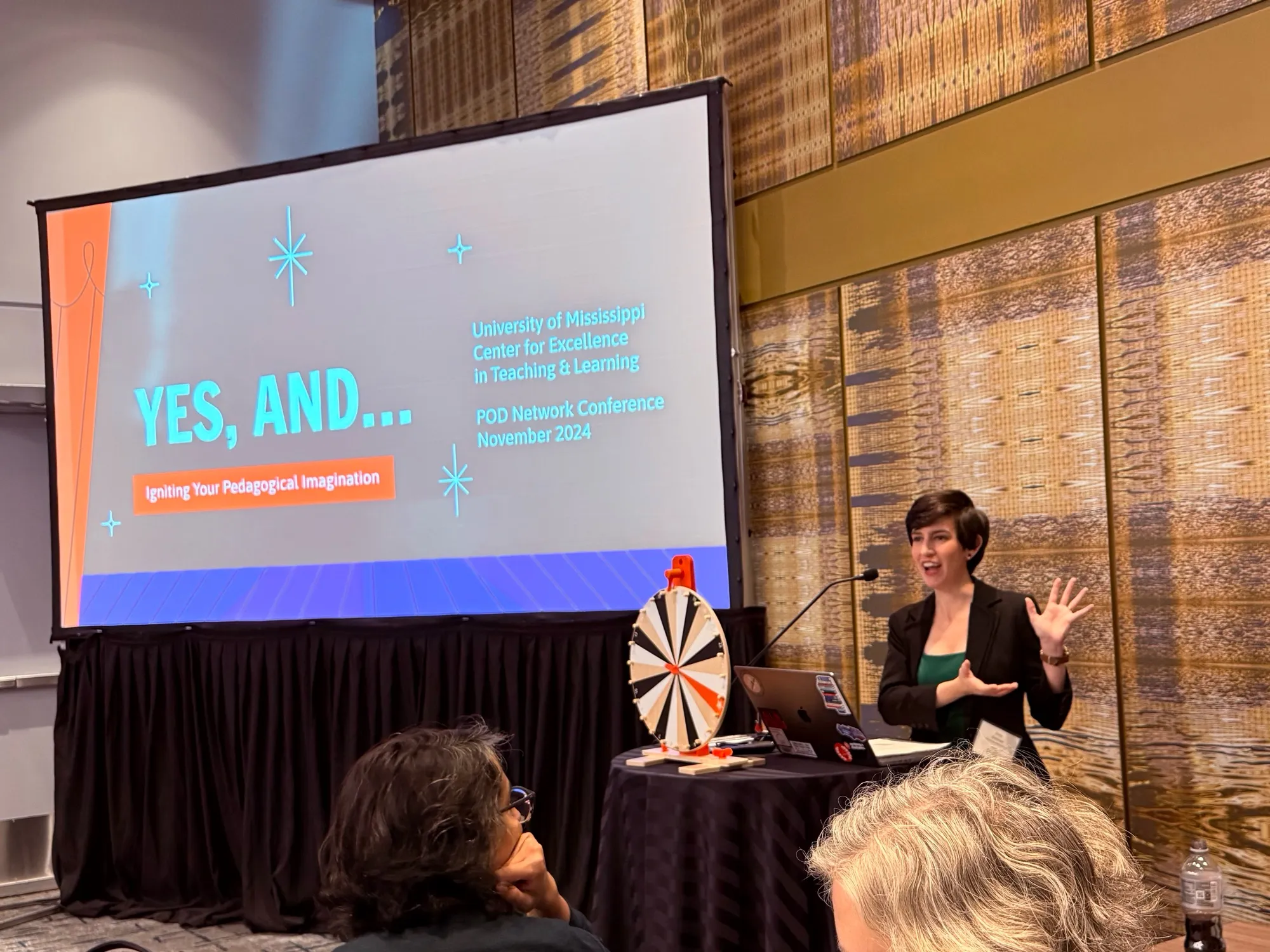 Emily gesturing mid-speech at a workshop