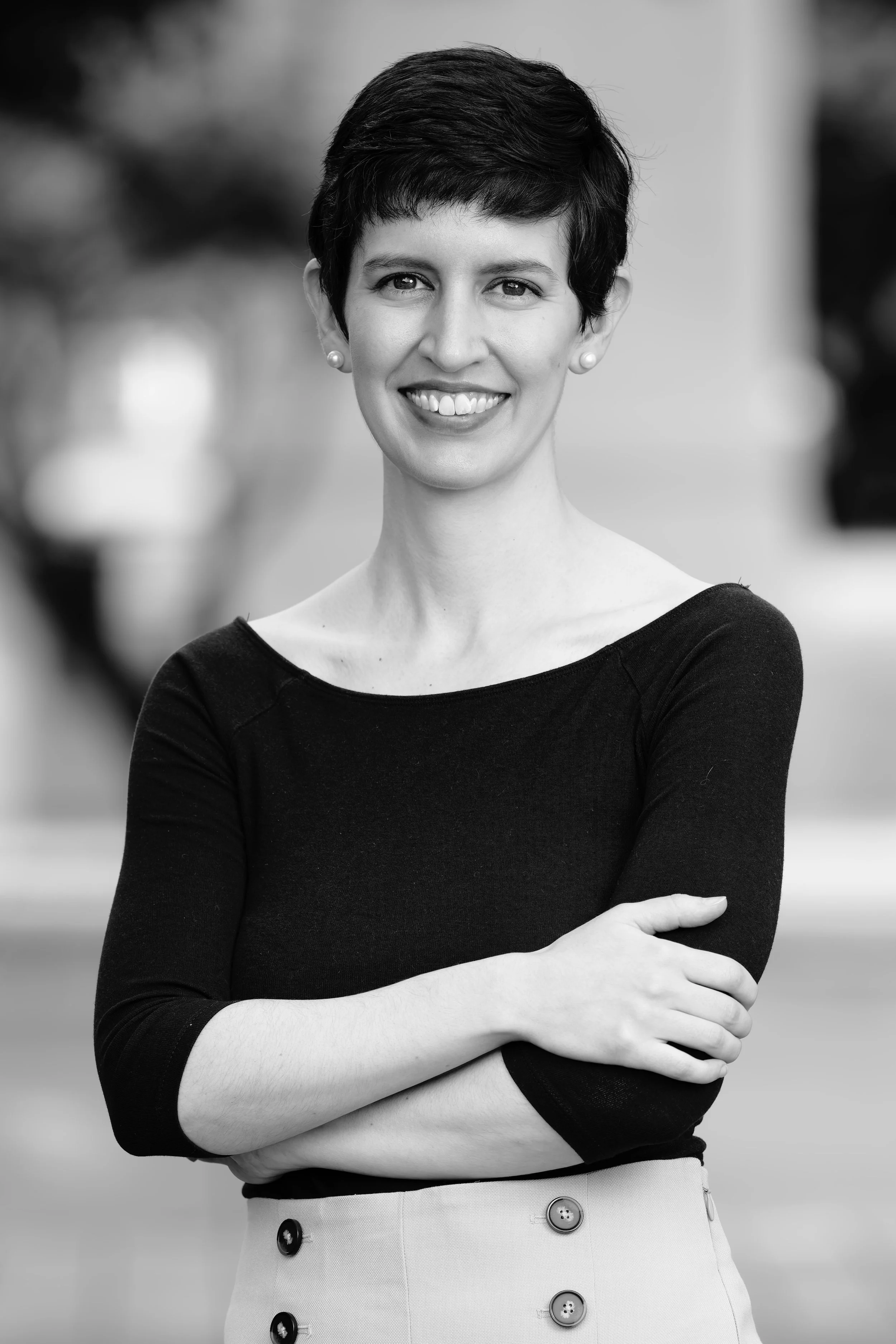 Black and white headshot of Emily, with arms crossed