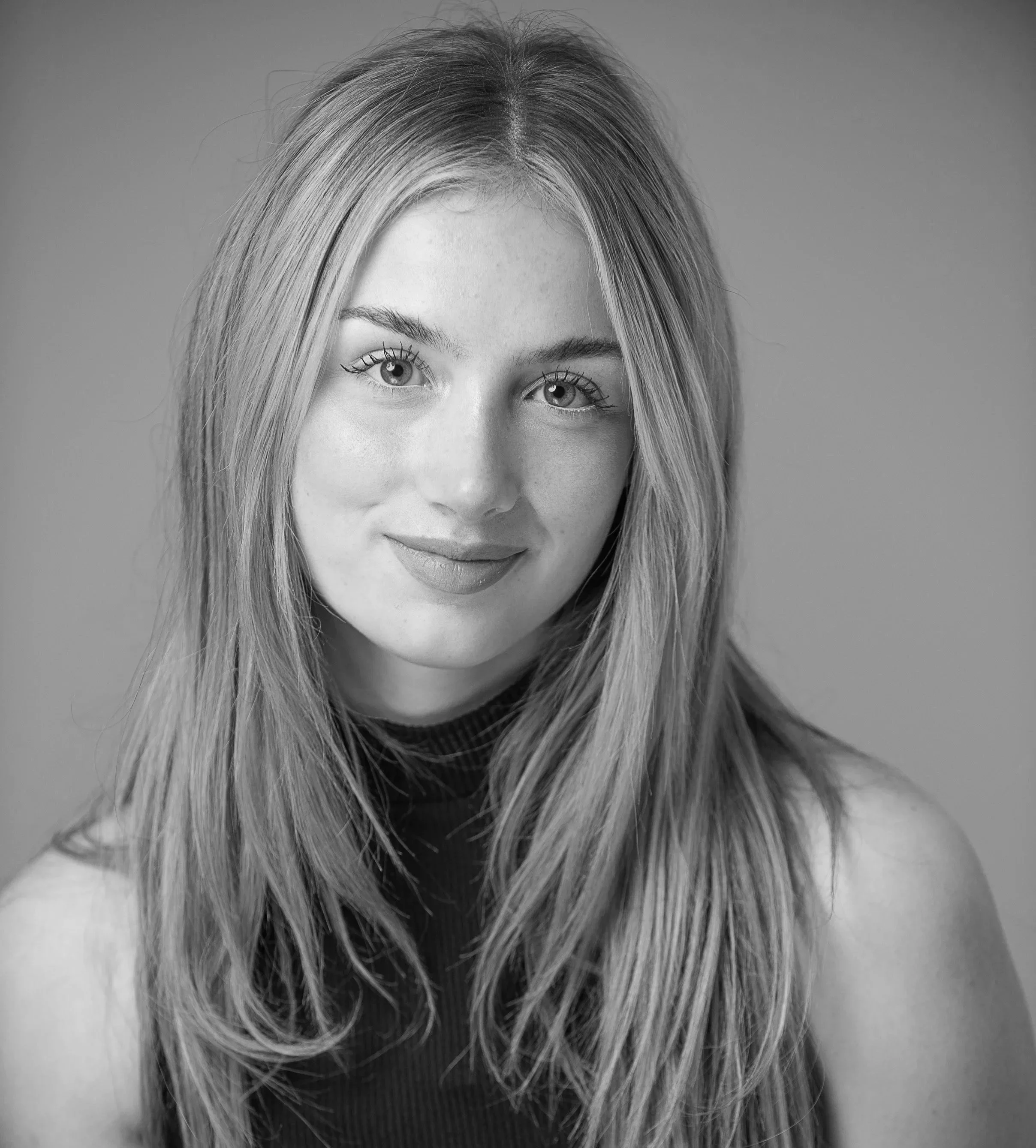 A black-and-white close-up photograph of a woman's face, showing her eyes, nose, lips, and long, flowing hair.