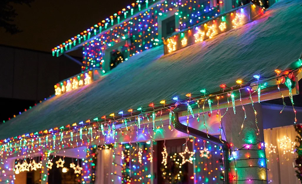House decorated with colorful Christmas lights on the roof and porch.