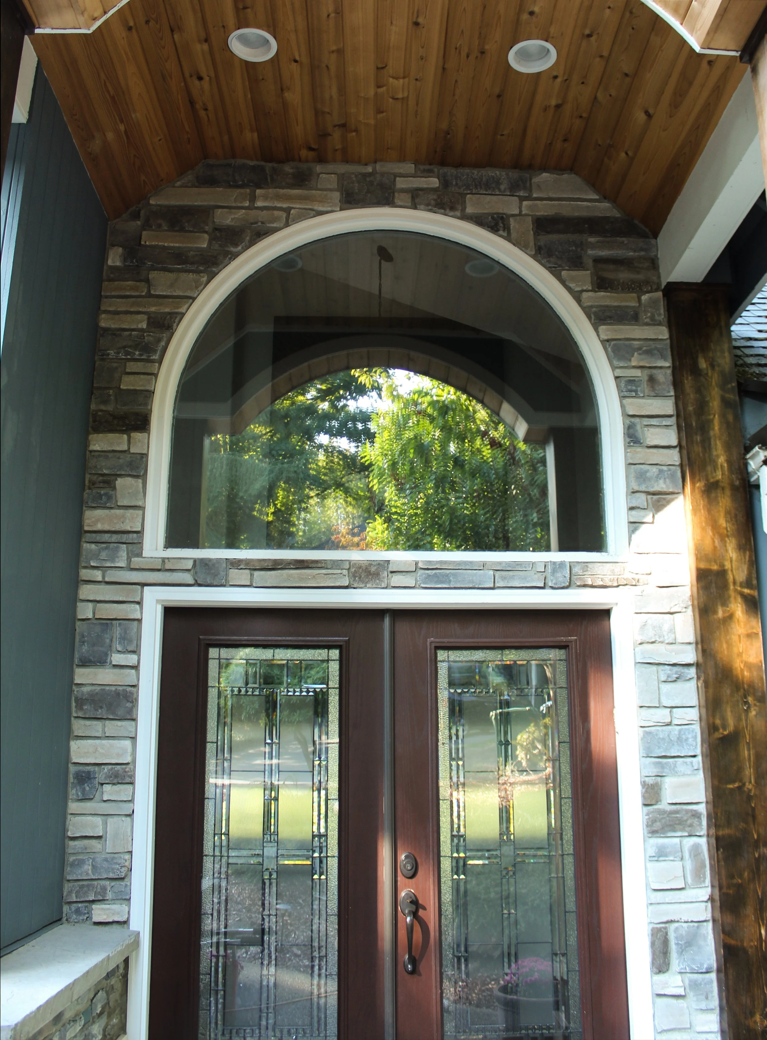 Custom entry door installation by F&M Construction & Remodeling on Mercer Island, WA, featuring decorative glass double front doors, an arched transom window, and exterior craftsmanship for luxury homes in Bellevue, Seattle, and the Eastside.
