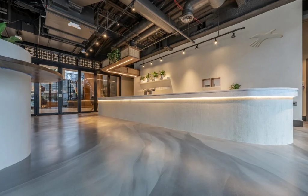 Modern, minimalistic reception desk in a spacious, well-lit interior with plants and decorative wall art.