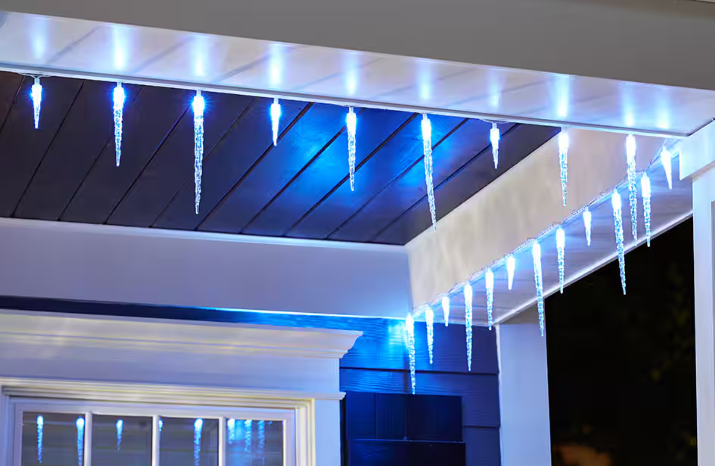 Blue icicle-shaped holiday lights hanging from the exterior ceiling of a house at night.